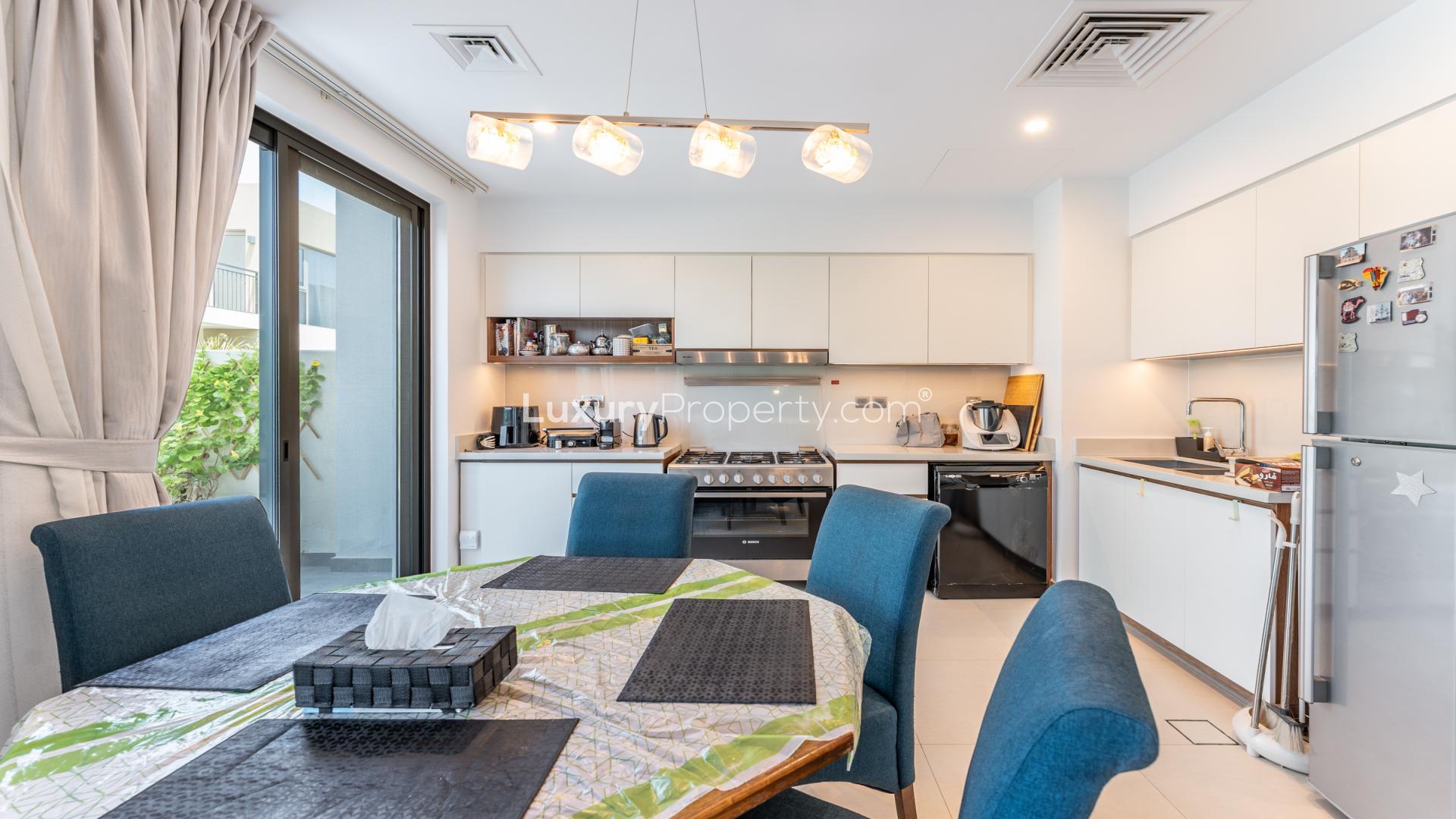 "Modern four-bedroom townhouse exterior in Camelia, Arabian Ranches 2, available for rent.",Modern kitchen and dining area in four-bedroom townhouse, Arabian Ranches 2, Camelia