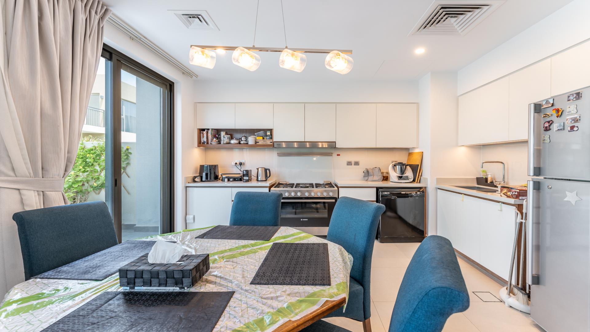 "Modern four-bedroom townhouse exterior in Camelia, Arabian Ranches 2, available for rent.",Modern kitchen and dining area in four-bedroom townhouse, Arabian Ranches 2, Camelia