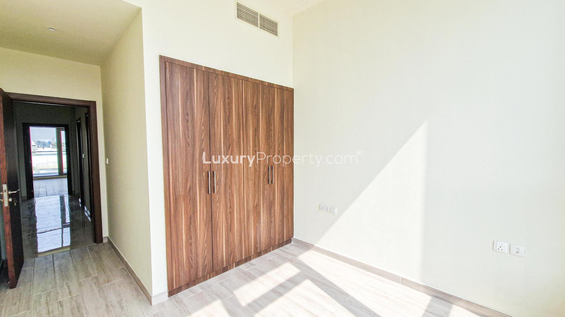 Bright bedroom with wooden wardrobe in Murano Al Furjan townhouse, available for rent