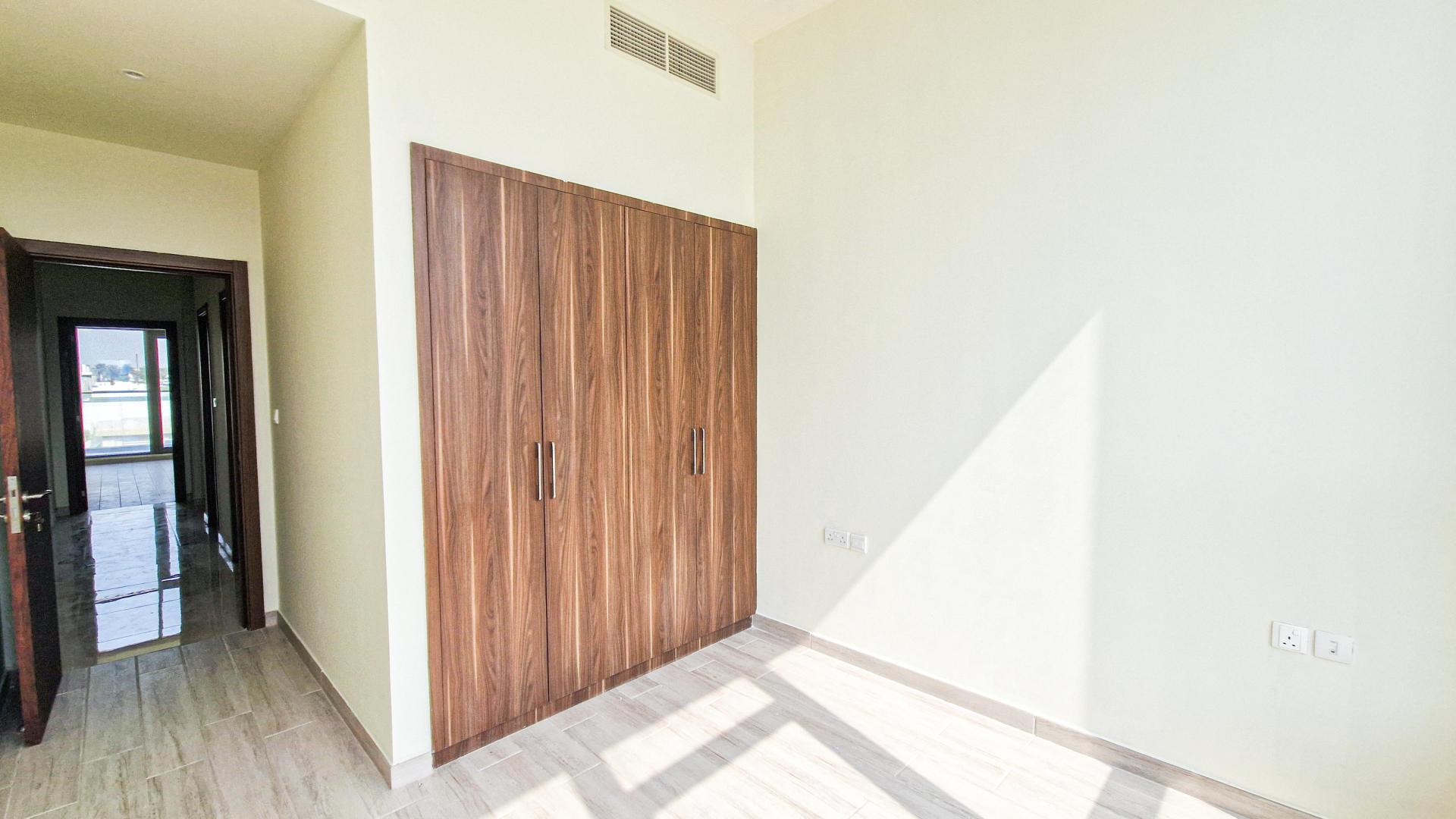Bright bedroom with wooden wardrobe in Murano Al Furjan townhouse, available for rent