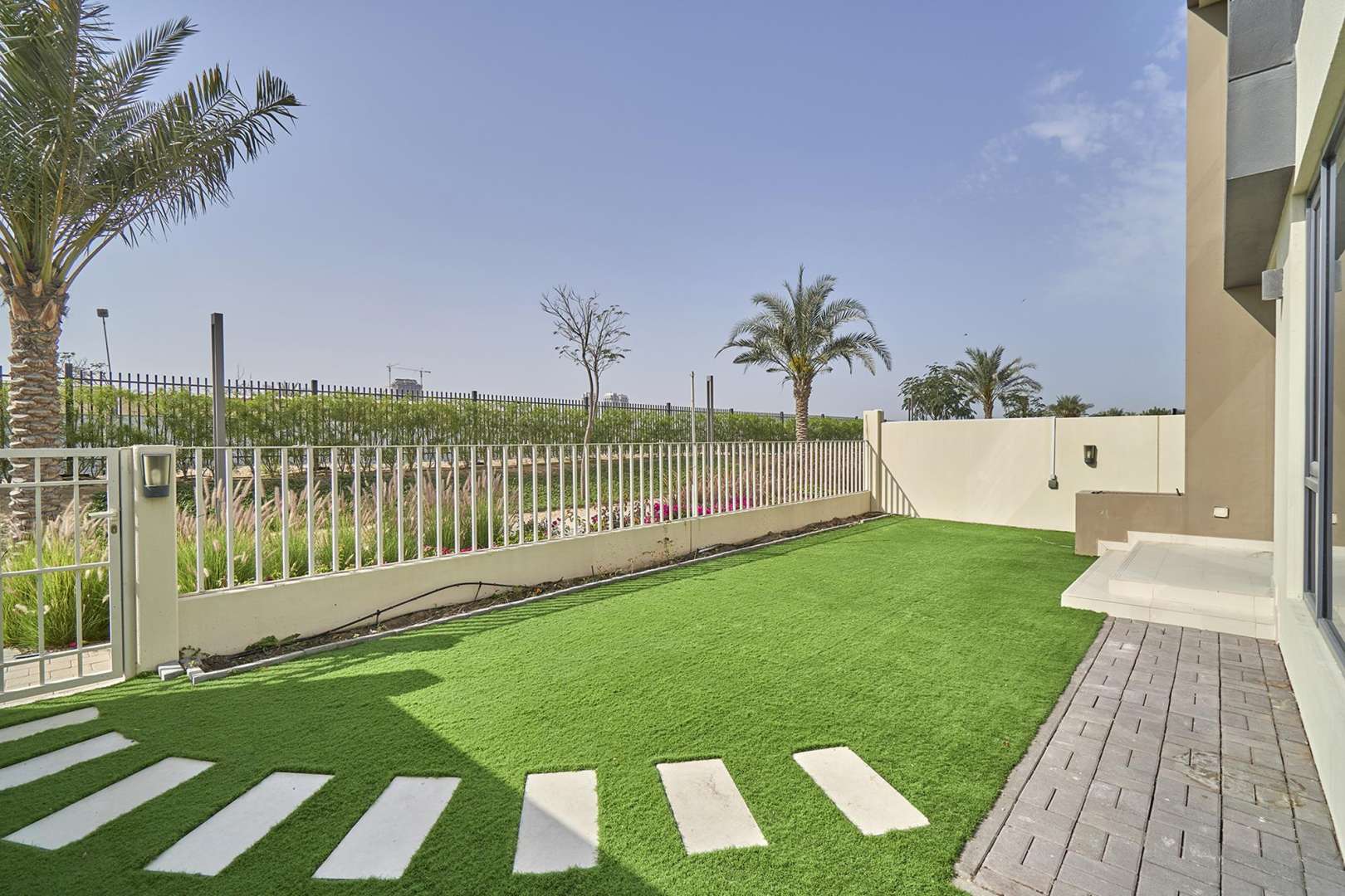Backyard view of townhouse in Maple 1, Dubai Hills Estate with artificial grass and palm trees