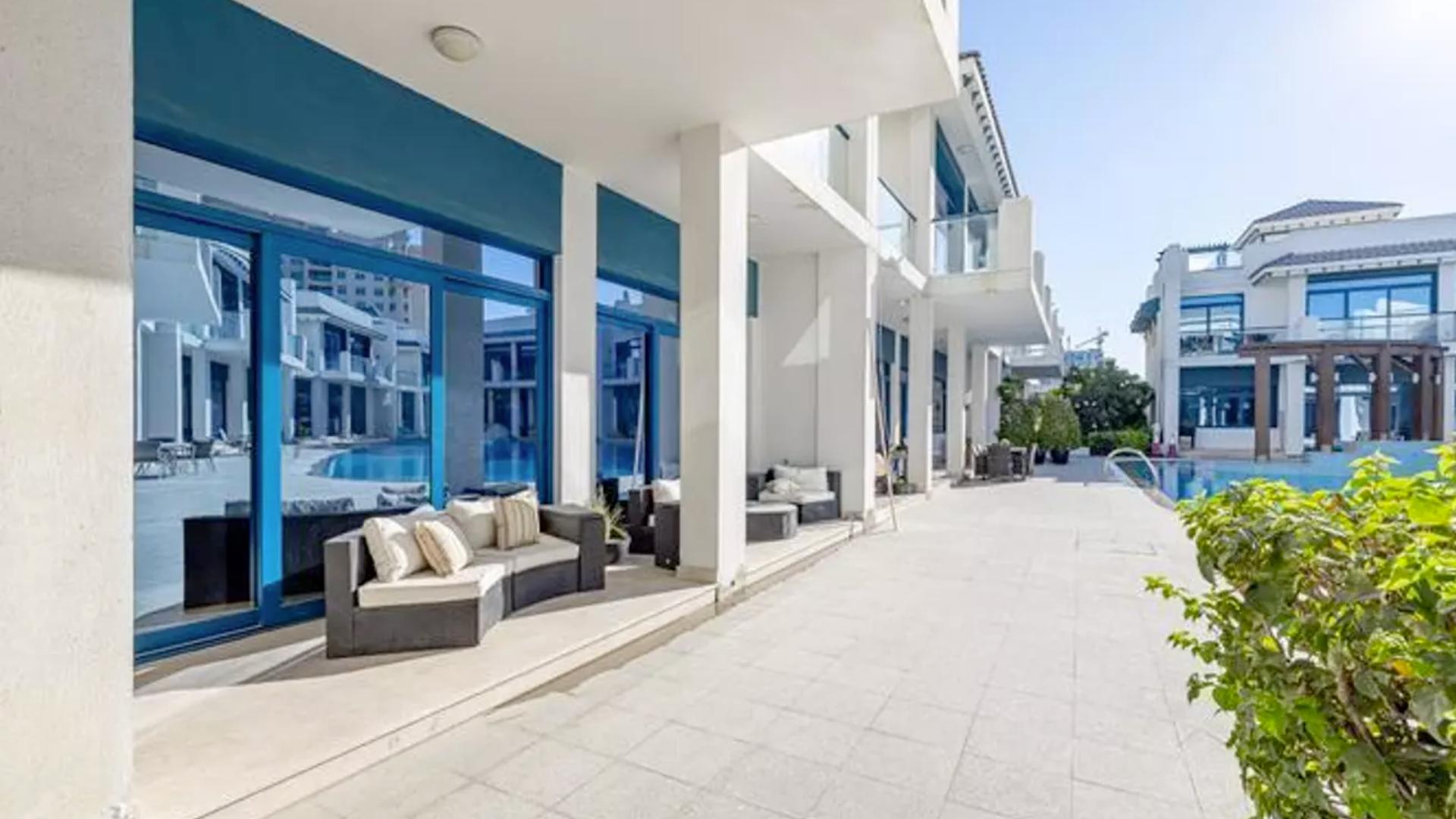 "Balcony view of Palma Residences townhouse overlooking pool in Palm Jumeirah, Dubai.",Beachfront townhouse patio with pool view at Palma Residences, Palm Jumeirah