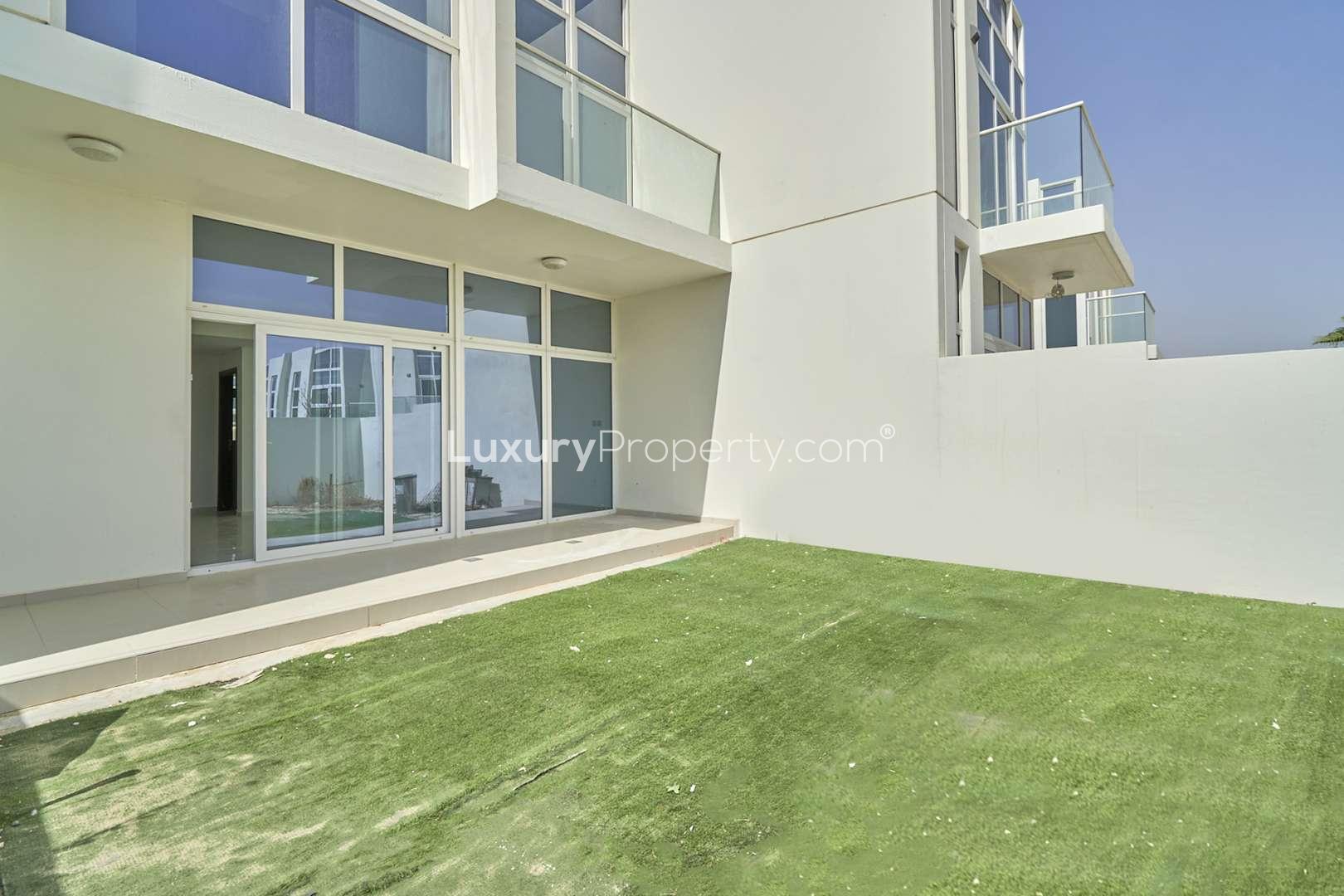 Luxurious villa exterior with glass doors and artificial lawn in Damac Hills 2, Akoya