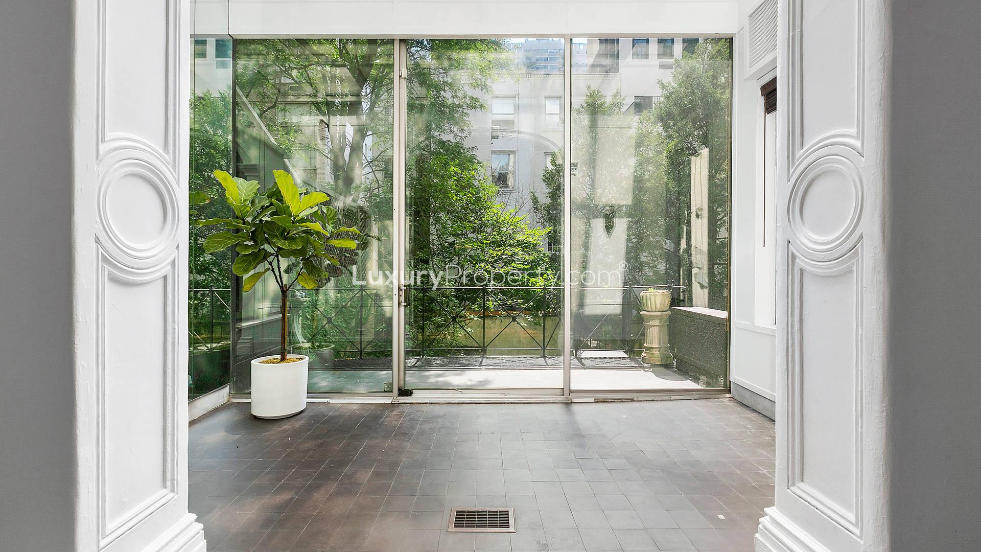 Elegant living room with fireplace in Manhattan townhouse, featuring hardwood floors and chandelier