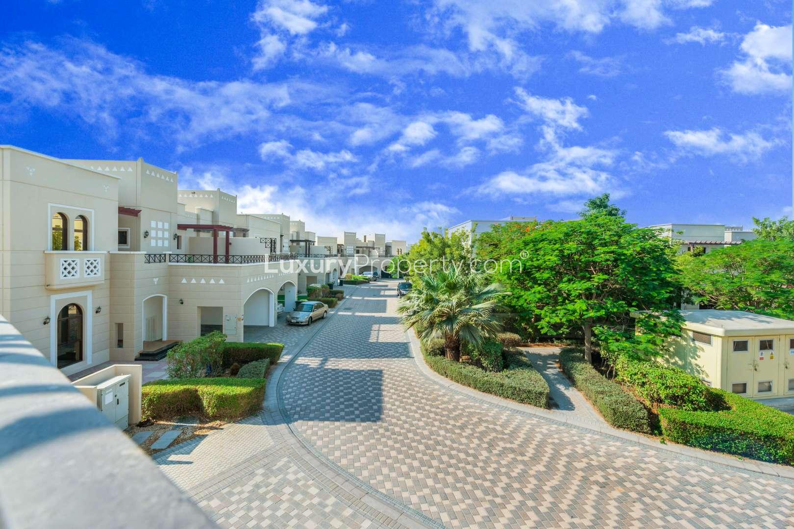 "Al Salam Mudon community townhouse street view with lush greenery and clear blue sky.",Spacious bathroom in Al Salam townhouse, Mudon Community, featuring modern fixtures and dual sinks