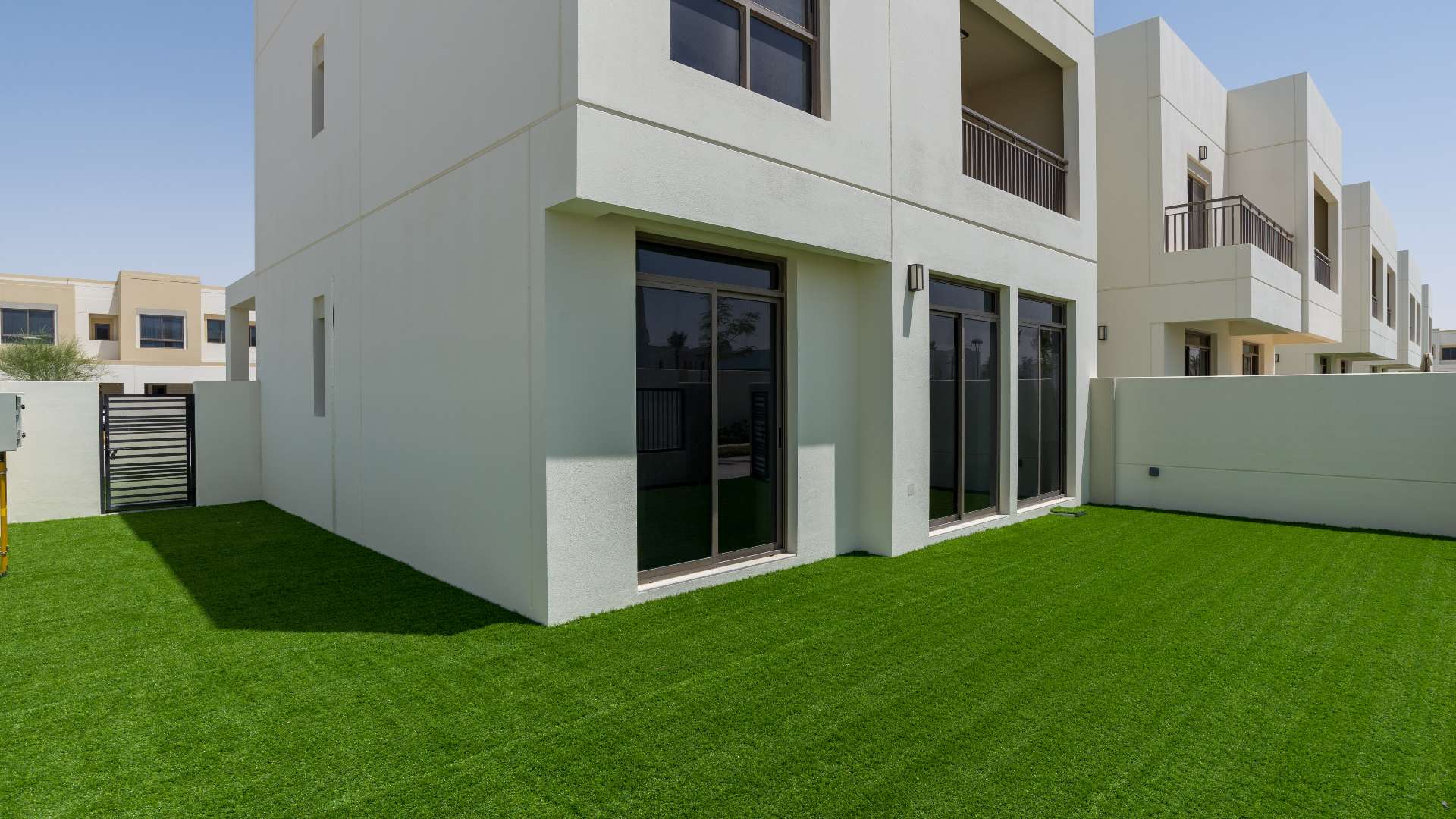 Exterior corner view of furnished 4-bedroom townhouse with green lawn in Naseem Town Square