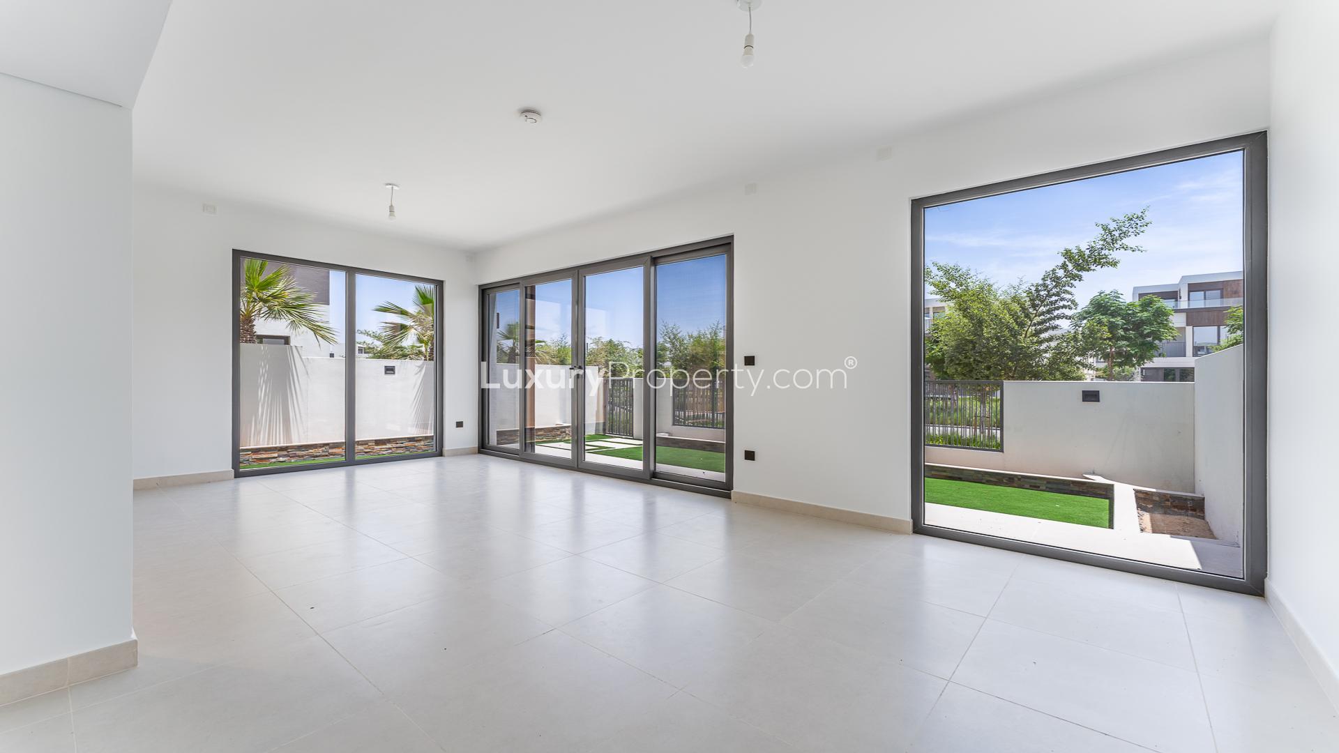 Bright living room with large windows overlooking garden in Aura, Tilal Al Ghaf villa