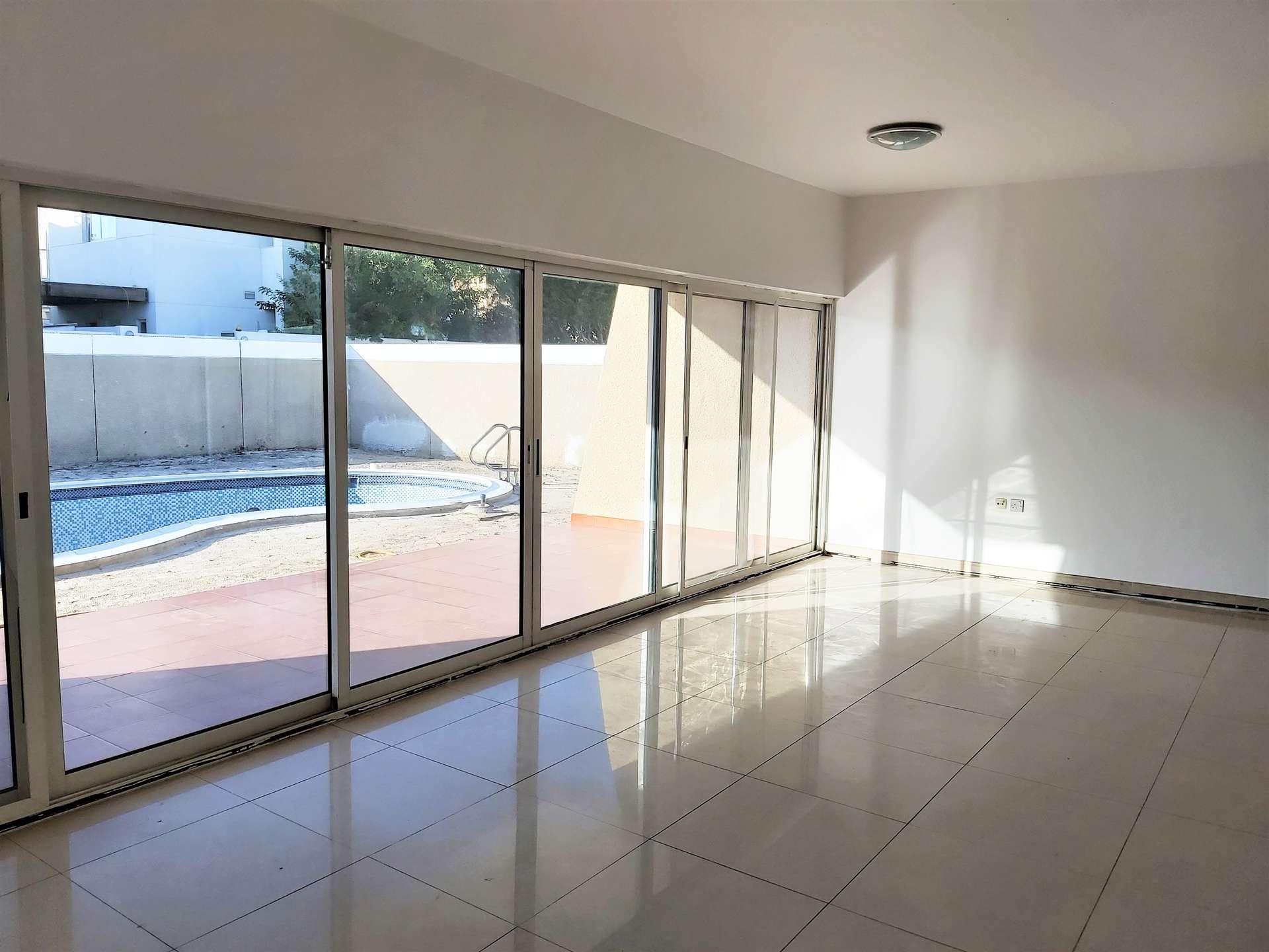 Spacious living area in Al Wasl villa for rent, featuring large windows and tiled floors