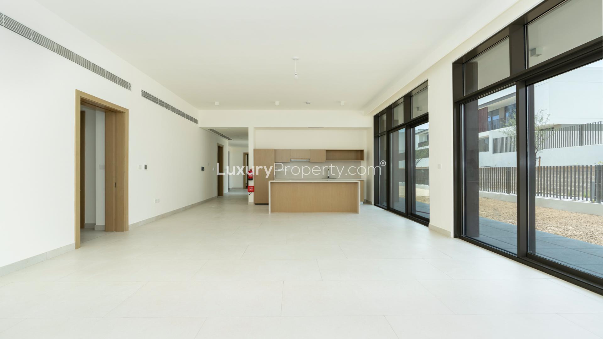 Bright, spacious living area in Al Furjan villa with large windows and open-plan kitchen