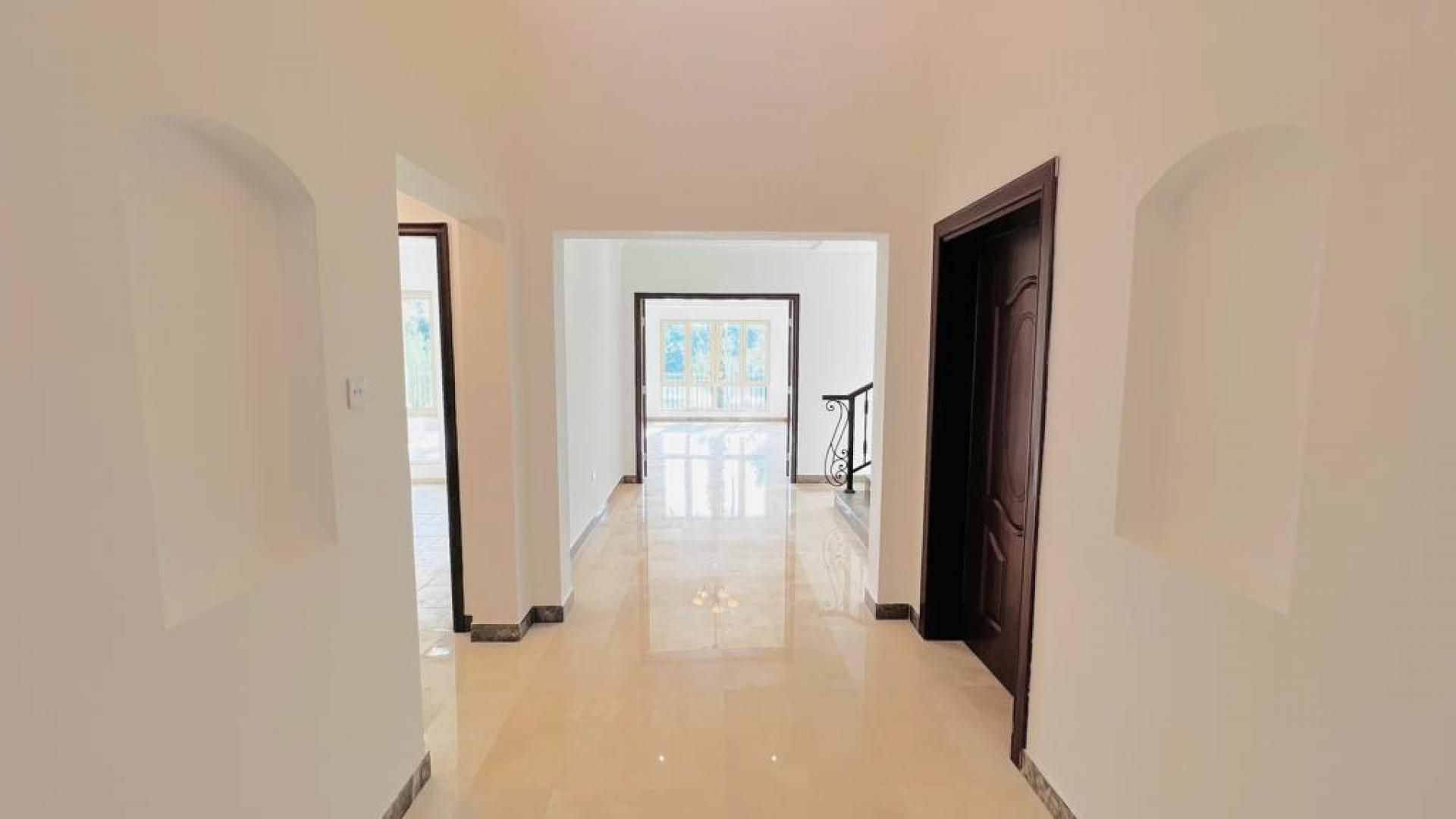 "Elegant 4-bedroom villa exterior with driveway, lush garden in Jumeirah Islands, Islamic Clusters.",Elegant hallway in Jumeirah Islands villa with marble floors and luxury finishes
