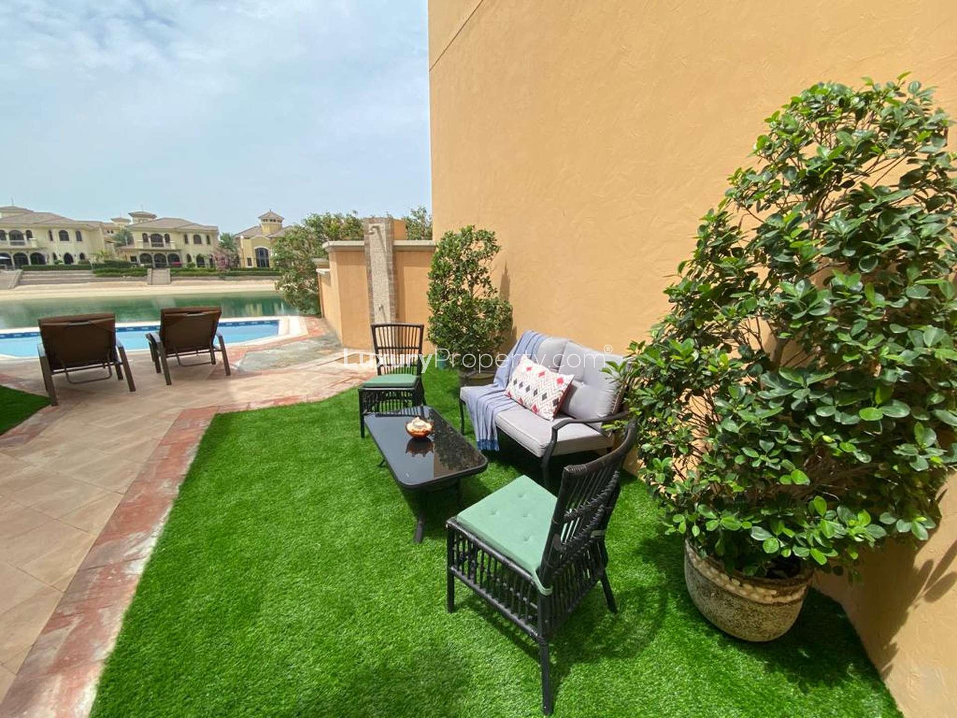 Elegant living room with plush sofa, large window, and garden view in Palm Jumeirah villa