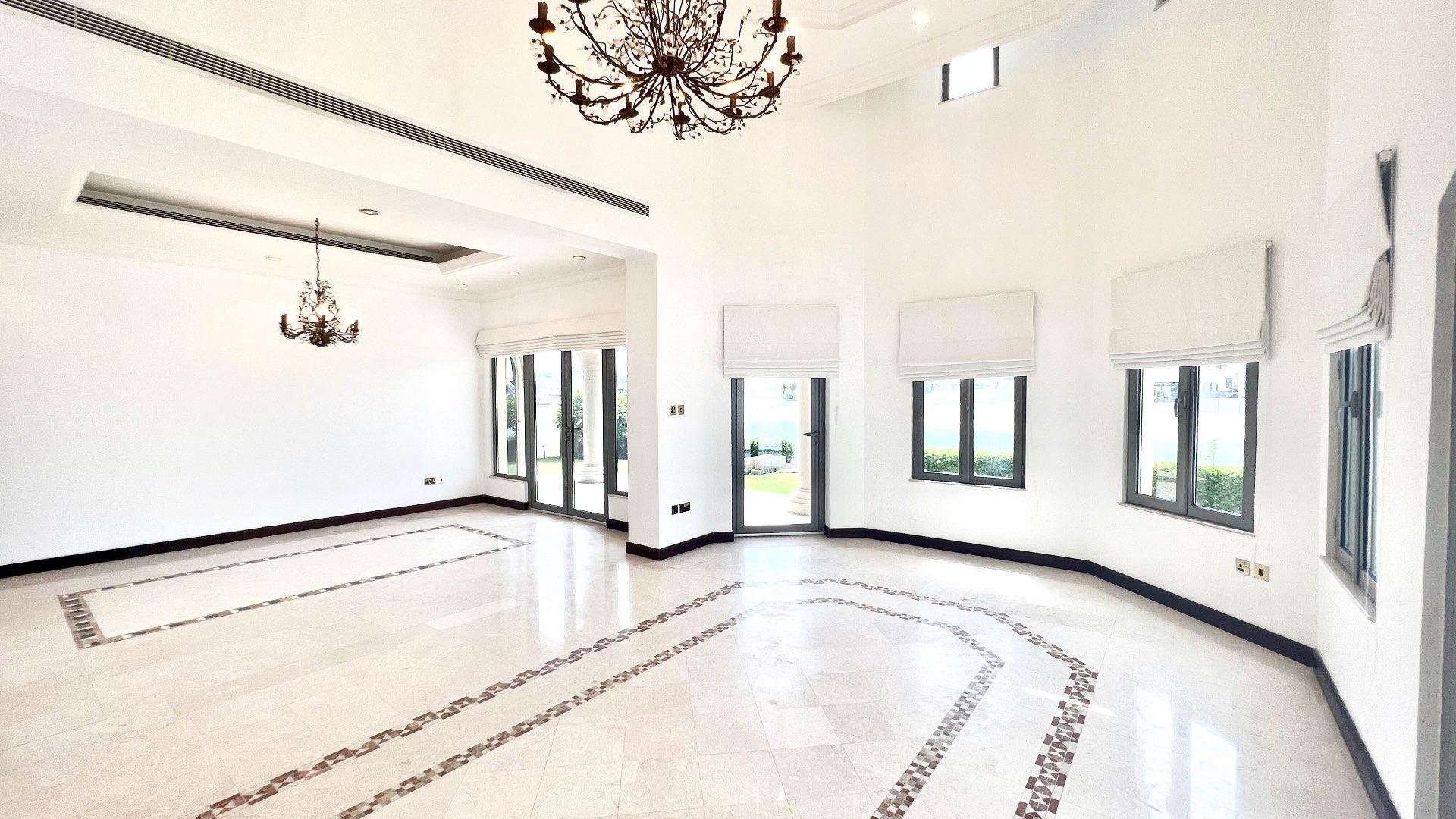 Spacious living room in Palm Jumeirah villa with large windows and elegant chandelier