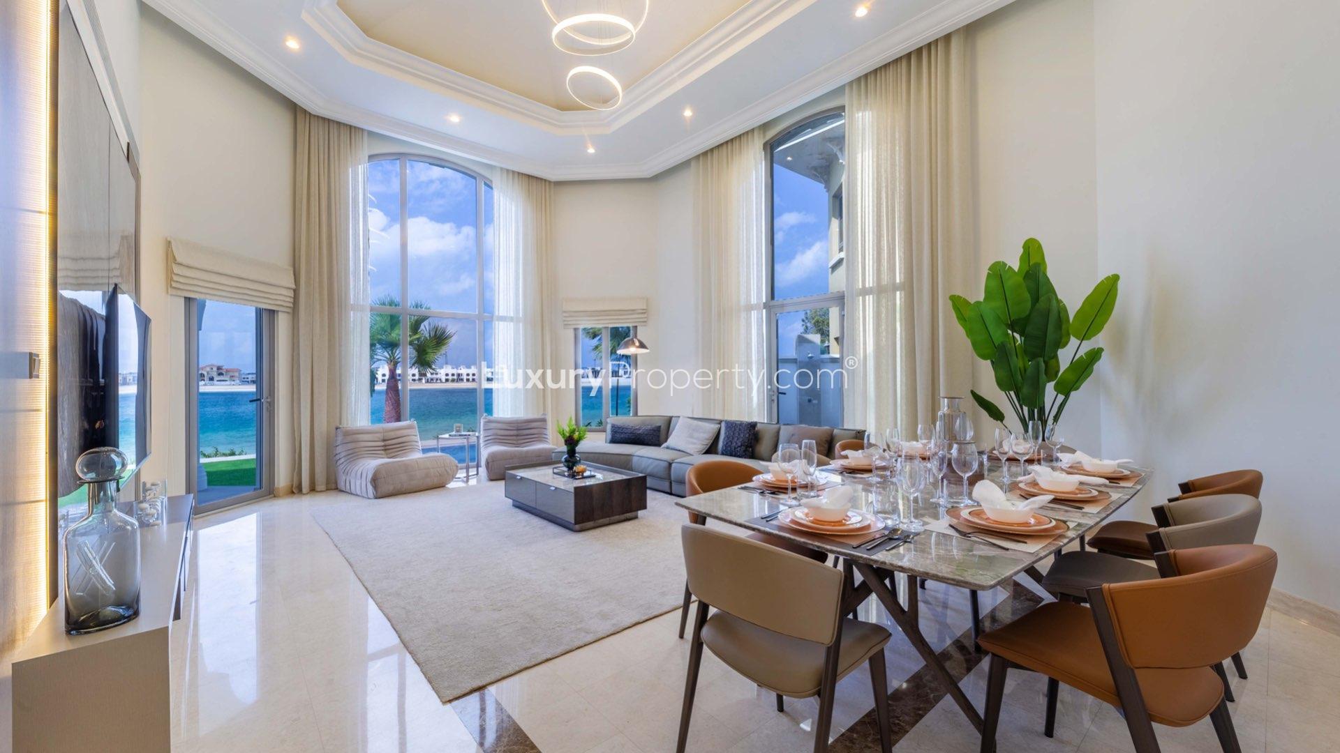 "Luxurious 4-bedroom villa exterior with landscaped garden in Palm Jumeirah, Garden Homes.",Luxurious living room and dining area in Palm Jumeirah 4-bedroom villa with sea view