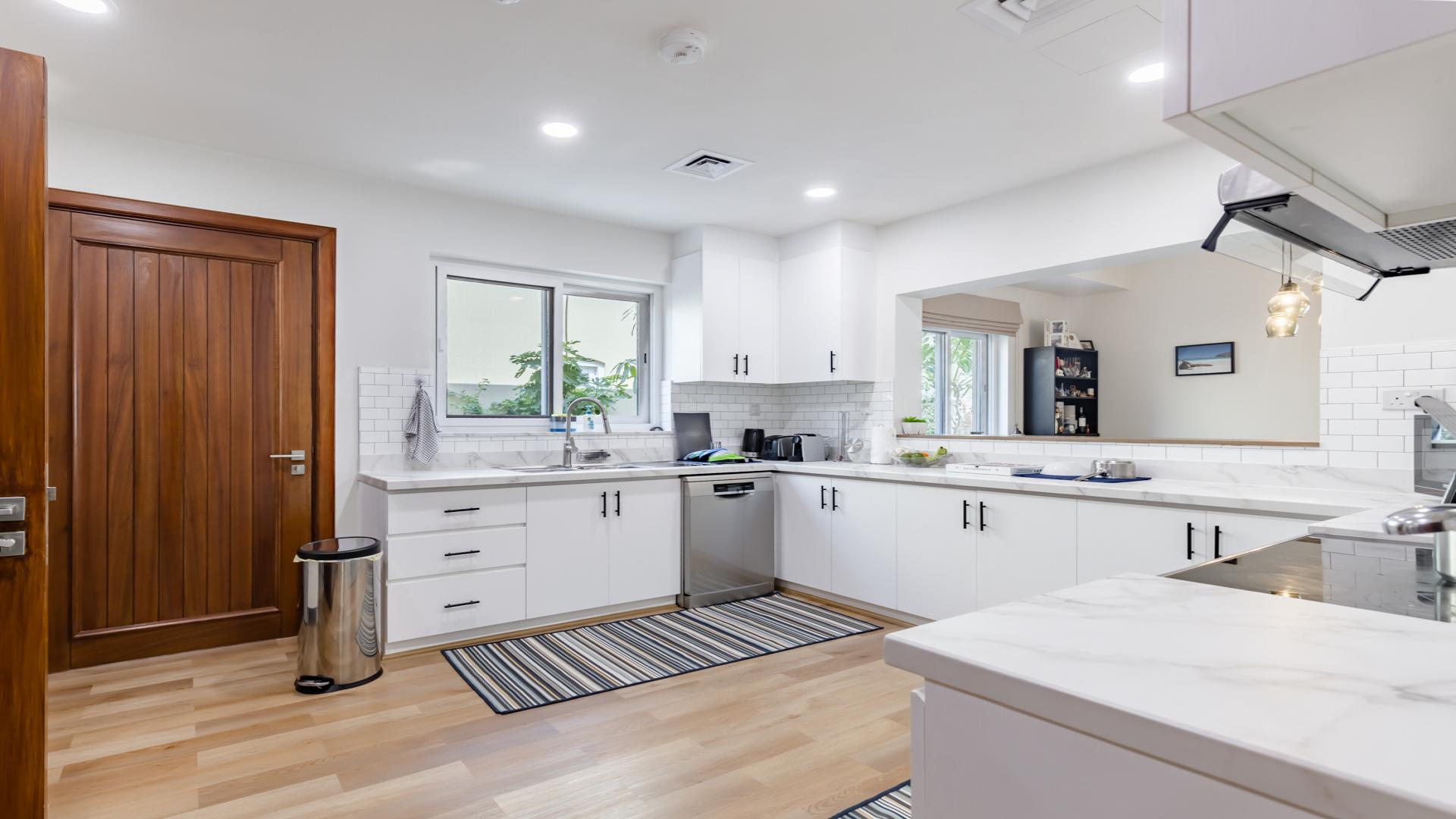 Modern kitchen in 4-bedroom La Quinta villa, Villanova, Dubai, with sleek white cabinetry