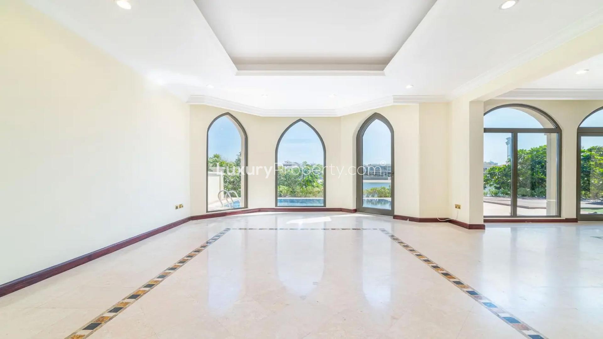Bright living room with large windows overlooking garden and pool in Palm Jumeirah villa