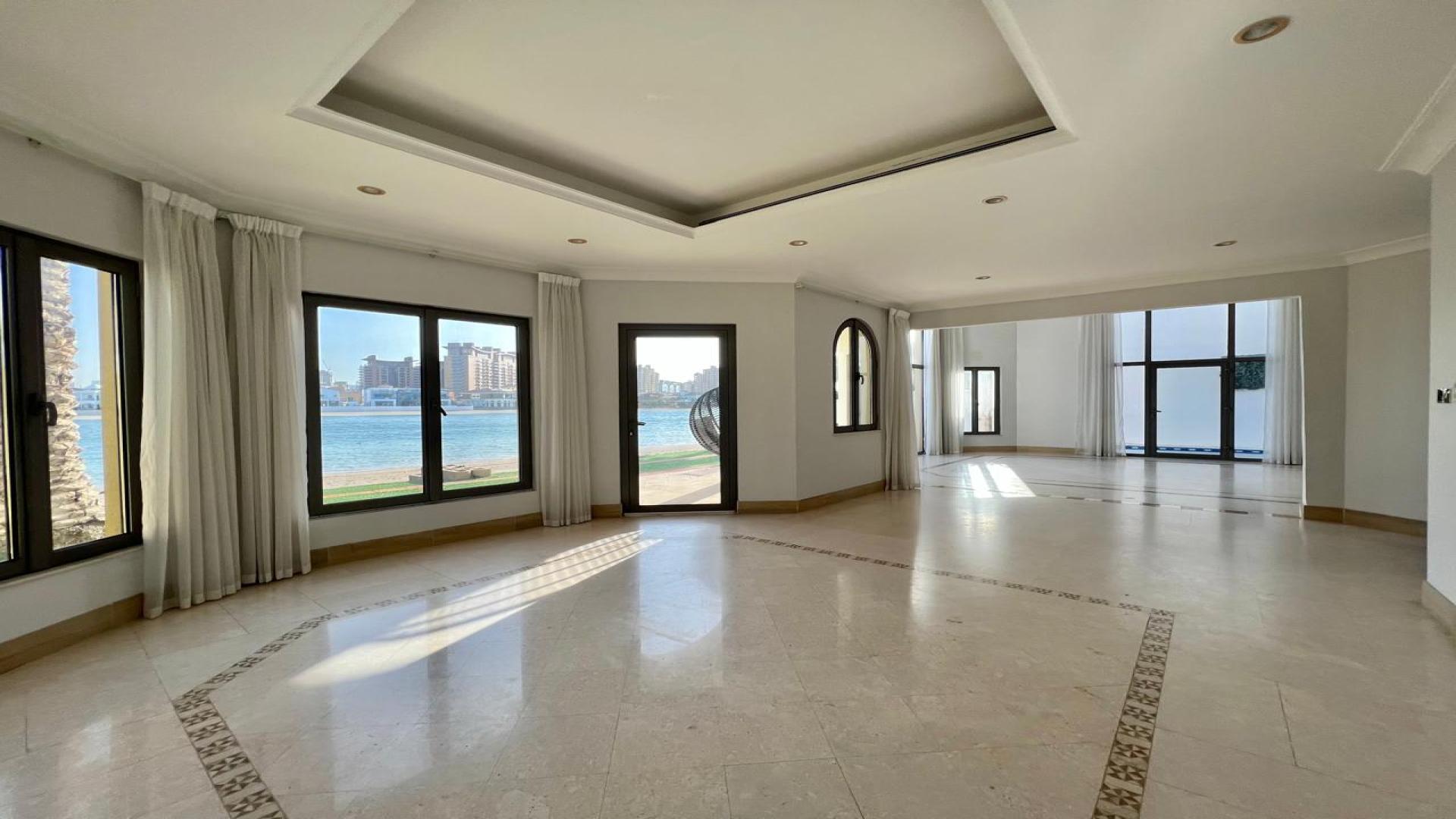 "Spacious living area with waterfront views in Palm Jumeirah Garden Homes Villa, Dubai.",Vacant villa interior with large windows in Palm Jumeirah Garden Homes Frond B