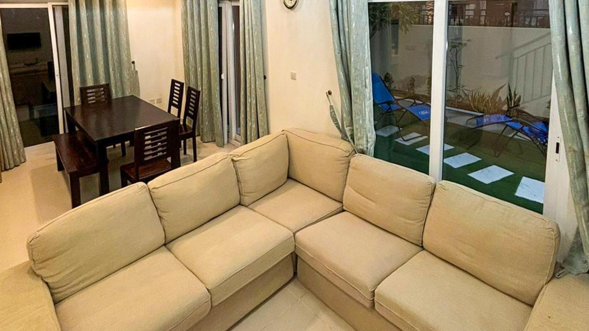 "Cozy living room with beige sofa in Amaranta 2 villa, Villanova, Dubai Land.",Living room with beige sofa, dining table, and pool view in Amaranta 2 villa