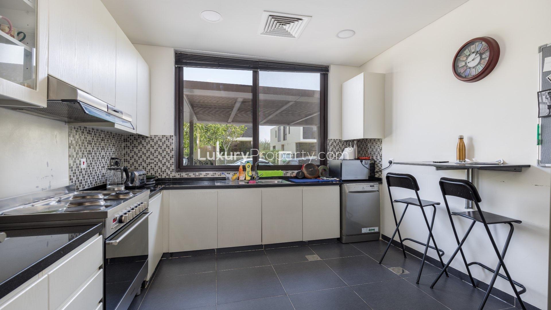 "Spacious backyard with slide and trampoline in Damac Hills Rochester villa for rent.",Modern kitchen in Rochester villa, Damac Hills, featuring sleek countertops and stylish appliances