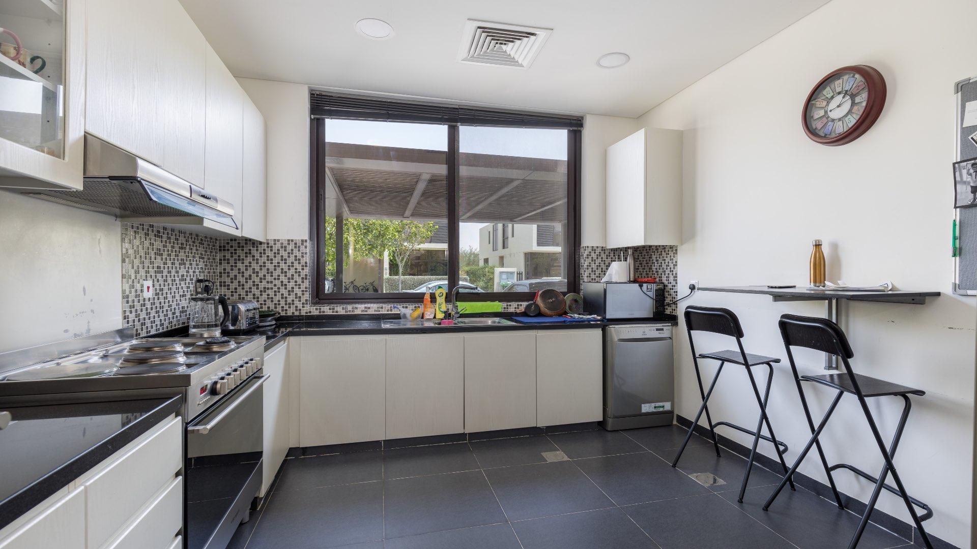 "Spacious backyard with slide and trampoline in Damac Hills Rochester villa for rent.",Modern kitchen in Rochester villa, Damac Hills, featuring sleek countertops and stylish appliances