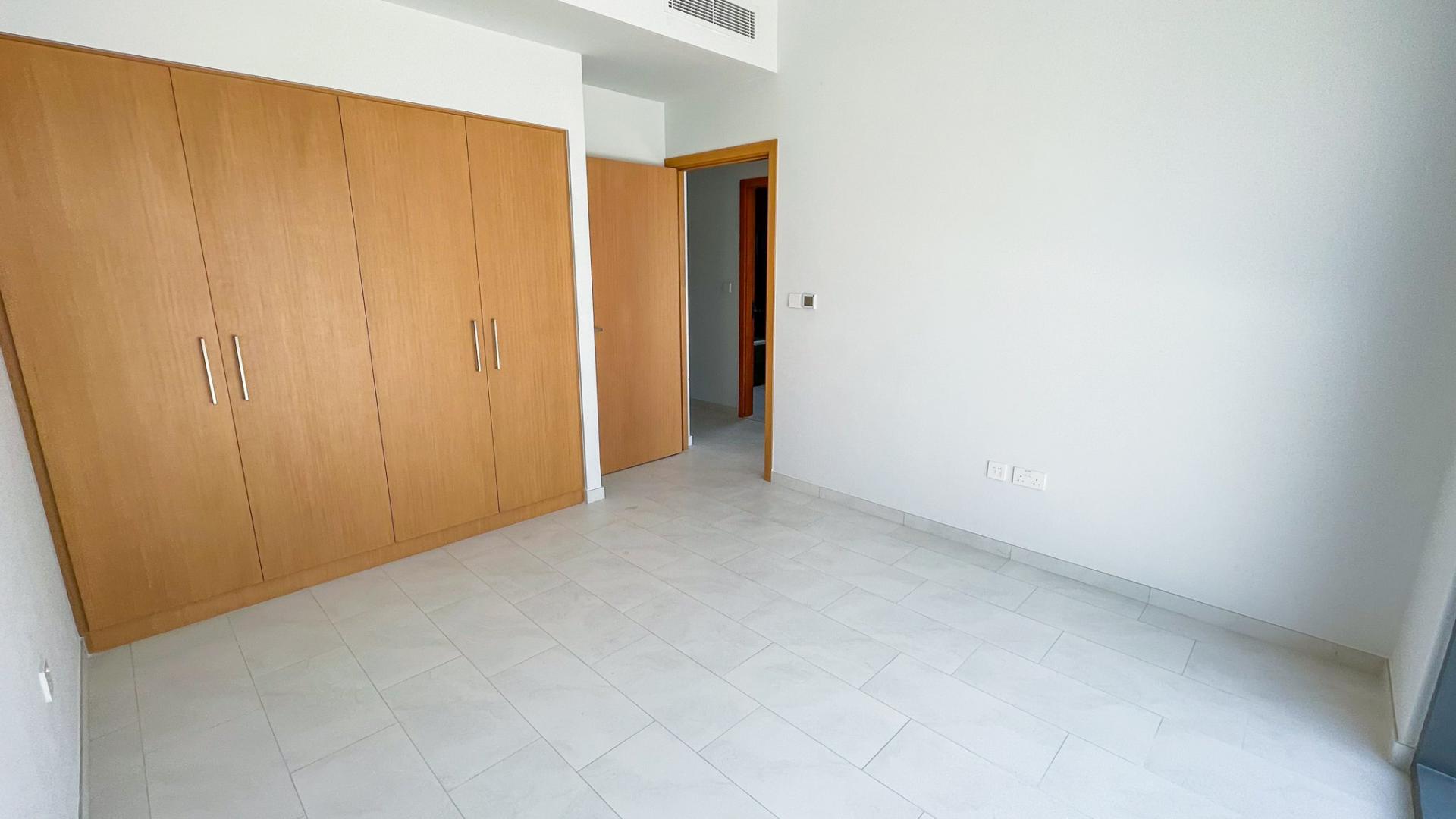 "Spacious living area with large windows in modern 4-bedroom villa, La Rosa 5, Dubai Land.",Empty bedroom with wooden closet in La Rosa 5, Villanova, Dubai Land villa for rent