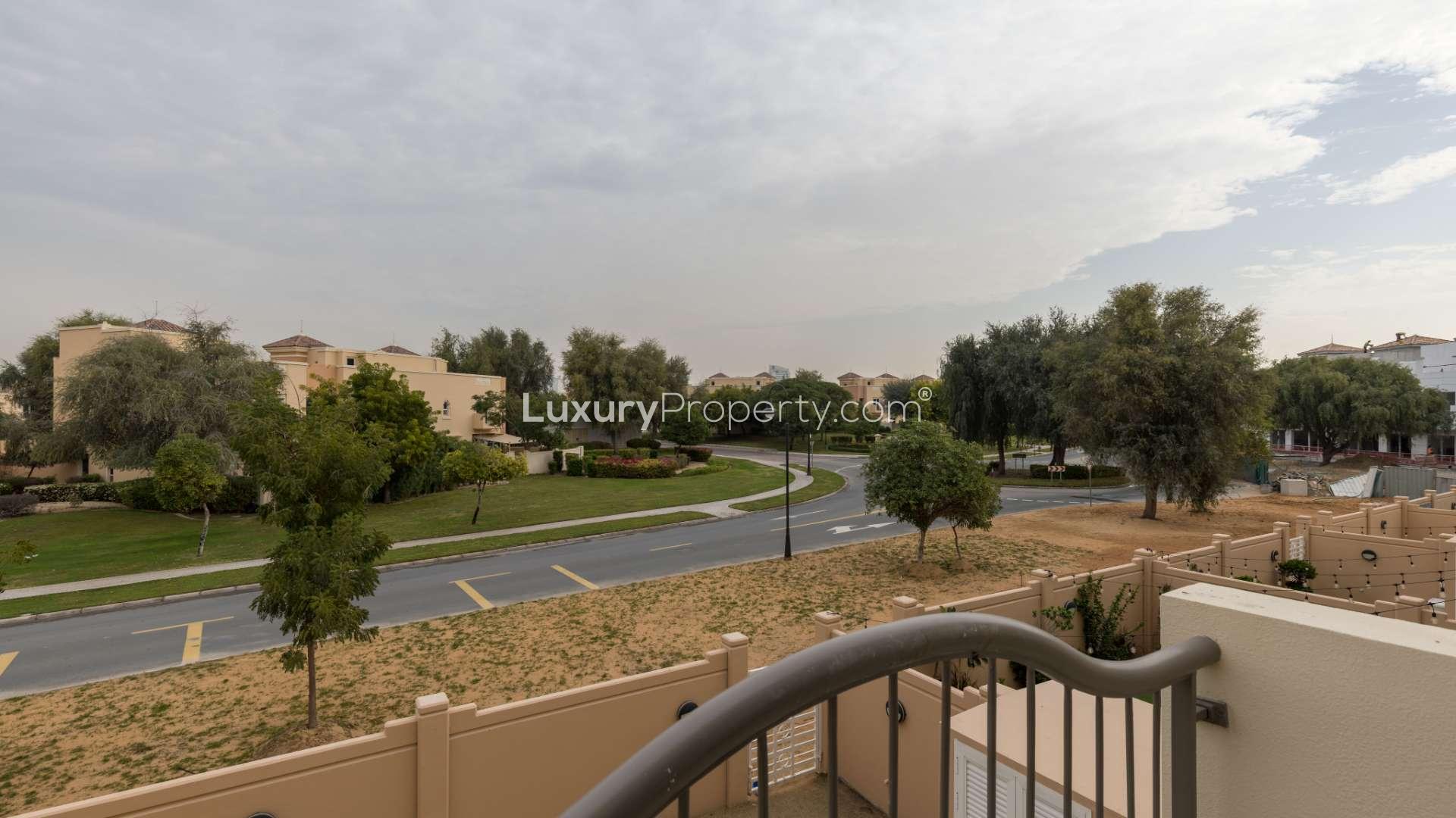 Elegant villa exterior in Victory Heights, Dubai Sports City, with palm trees and archways