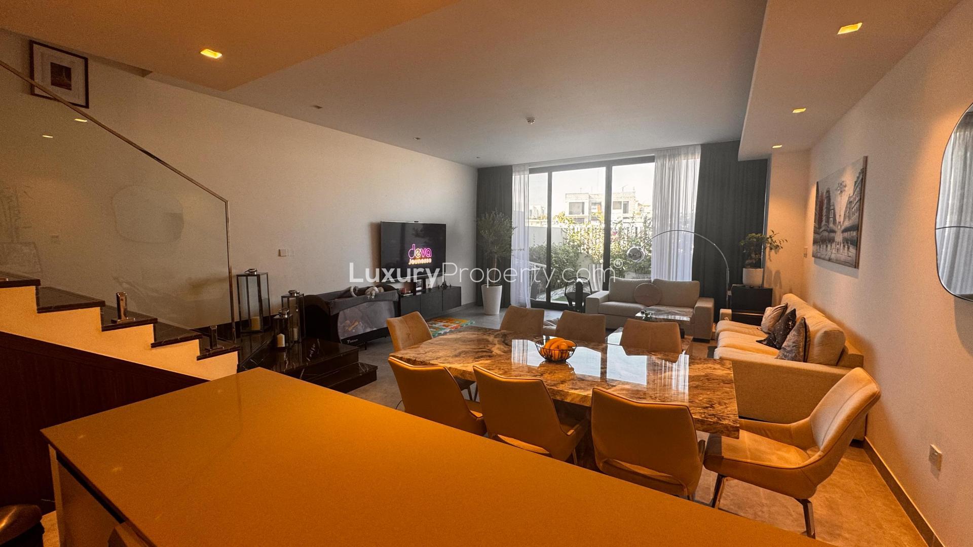 Outdoor seating area in Al Furjan West villa for sale, featuring lush greenery