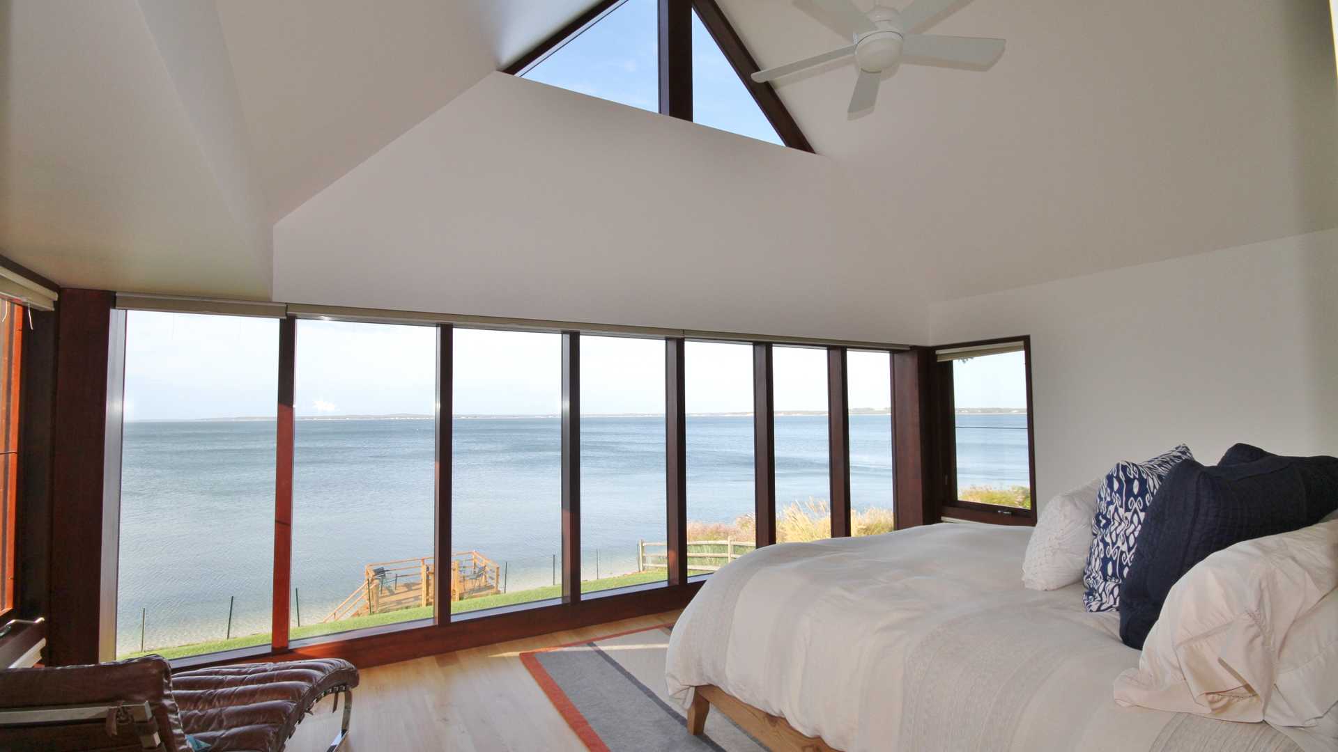 "Stunning ocean view from villa terrace at 43 Noyac Bay Avenue, Hamptons, New York.",Luxurious bedroom with stunning waterfront view at Hamptons villa, 43 Noyac Bay Avenue