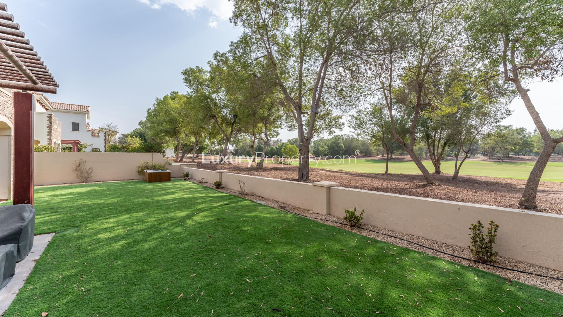 Villa backyard with lush lawn and scenic golf course views at Jumeirah Golf Estates