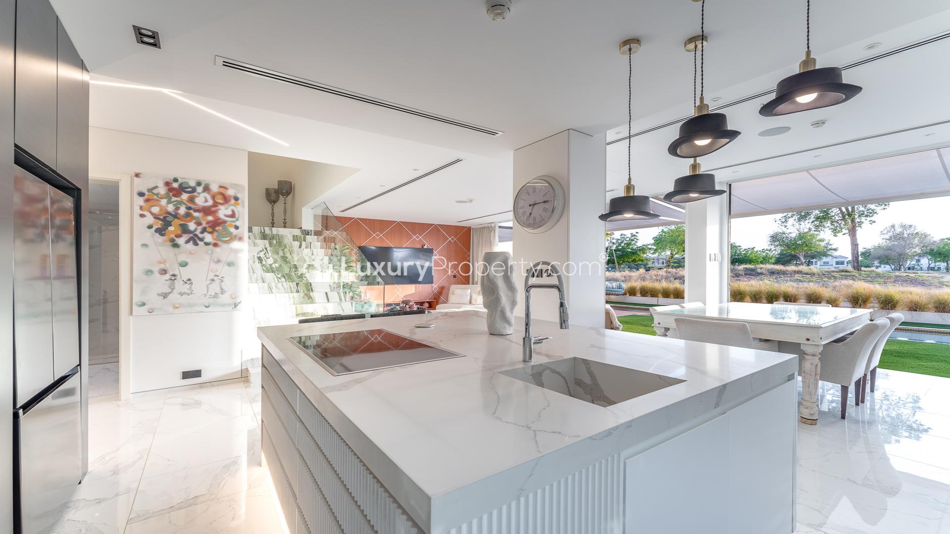 "Poolside view of golf course and skyline at Jumeirah Golf Estates villa for sale.",Modern kitchen and dining area in Jumeirah Golf Estates villa with golf course view