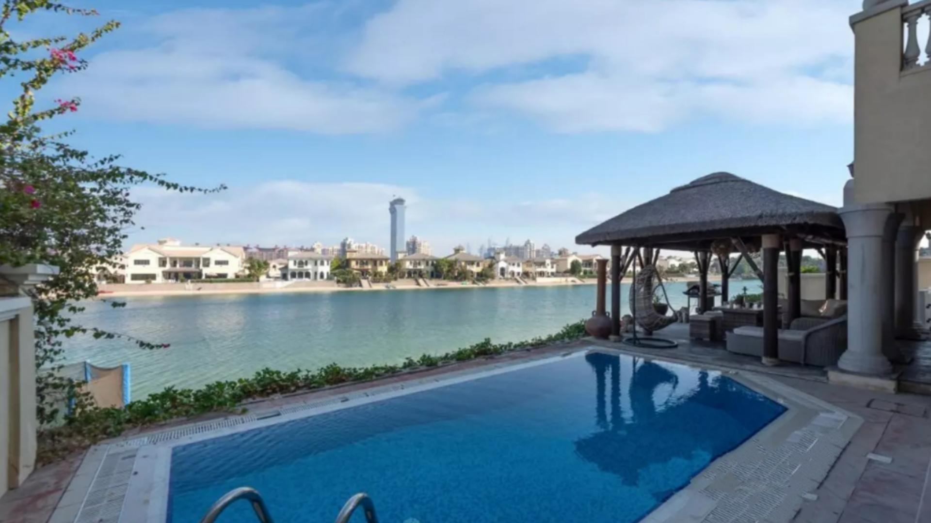 Outdoor seating area with thatched pergola overlooking water in Palm Jumeirah villa