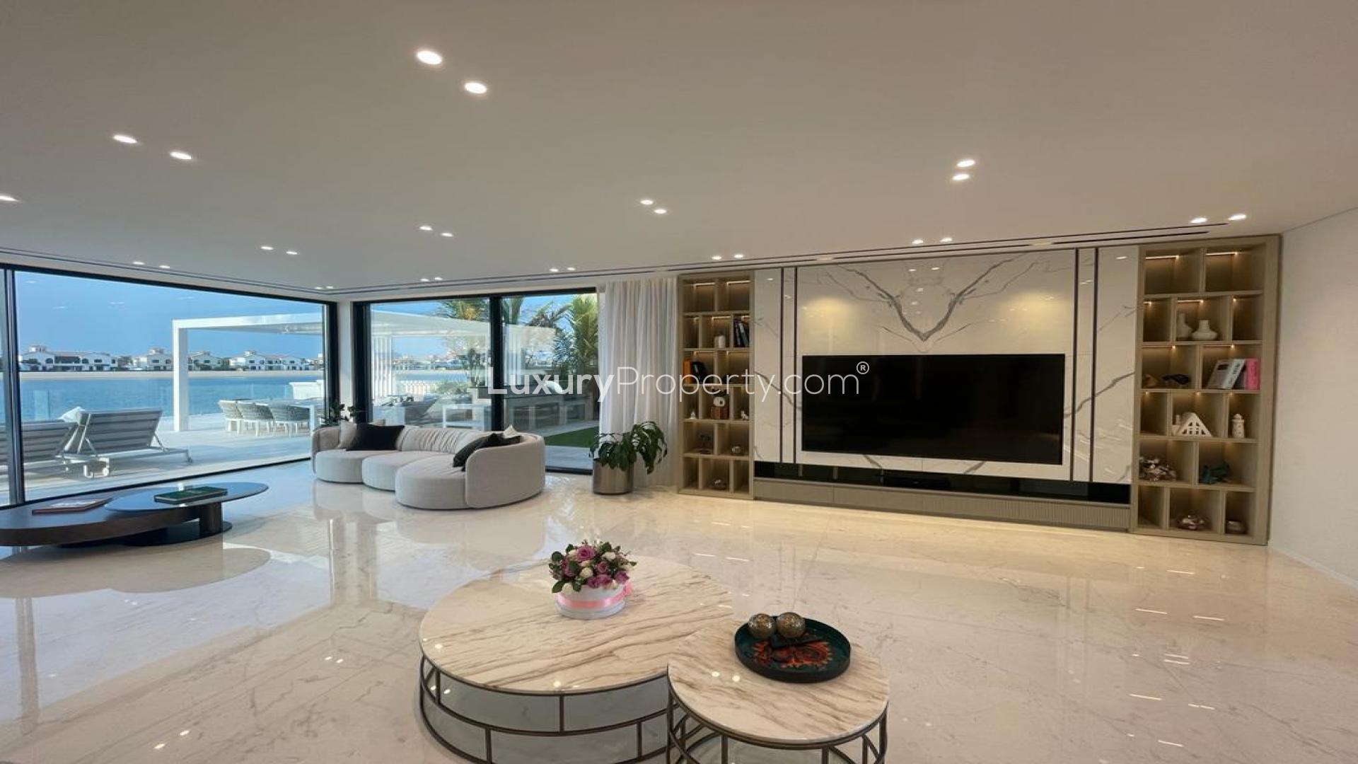"Luxurious Palm Jumeirah villa with infinity pool and beachfront sunset view for sale.",Luxurious living room in renovated Palm Jumeirah villa with waterfront views and modern decor