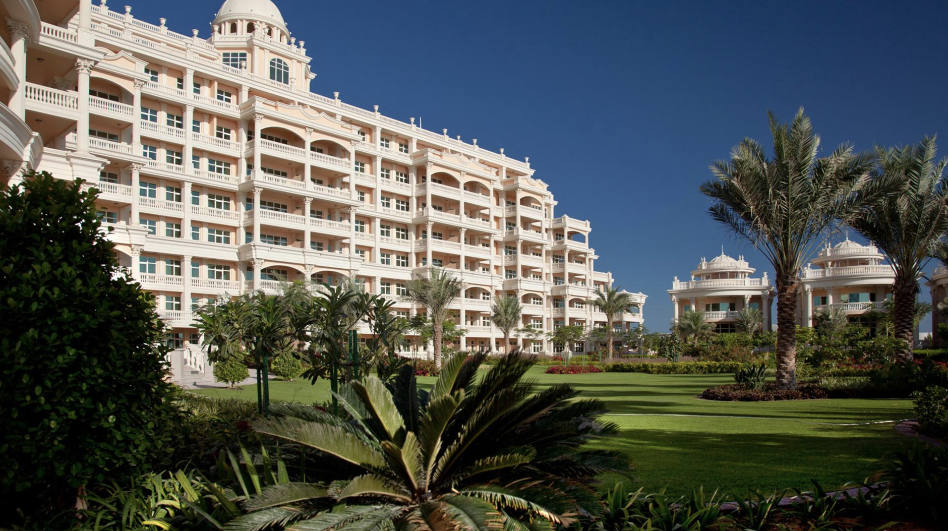 Luxurious villa exterior in Kempinski Palm Residences with lush gardens and palm trees
