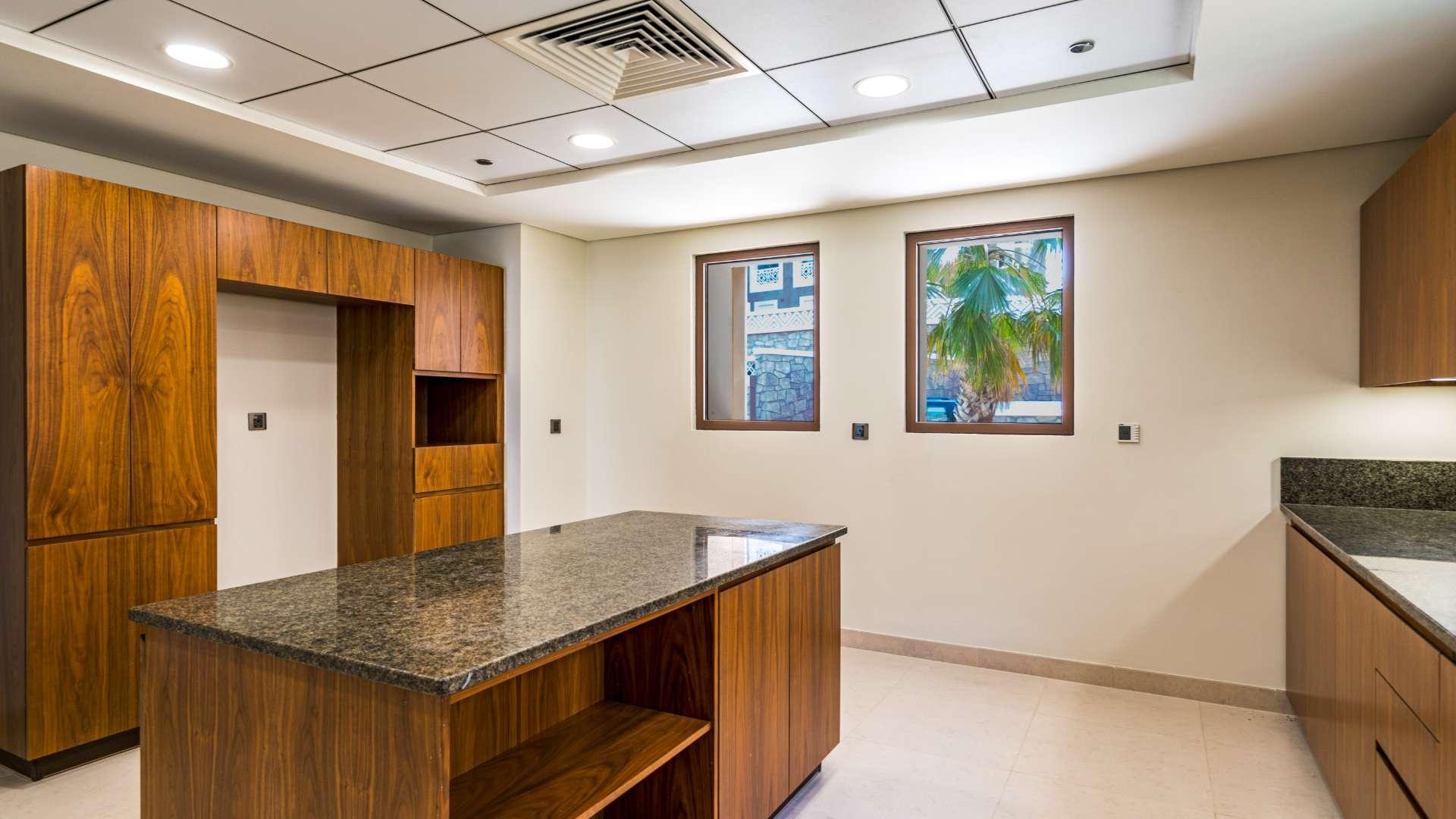 Modern kitchen in Palm Jumeirah villa with wooden cabinets and granite countertops