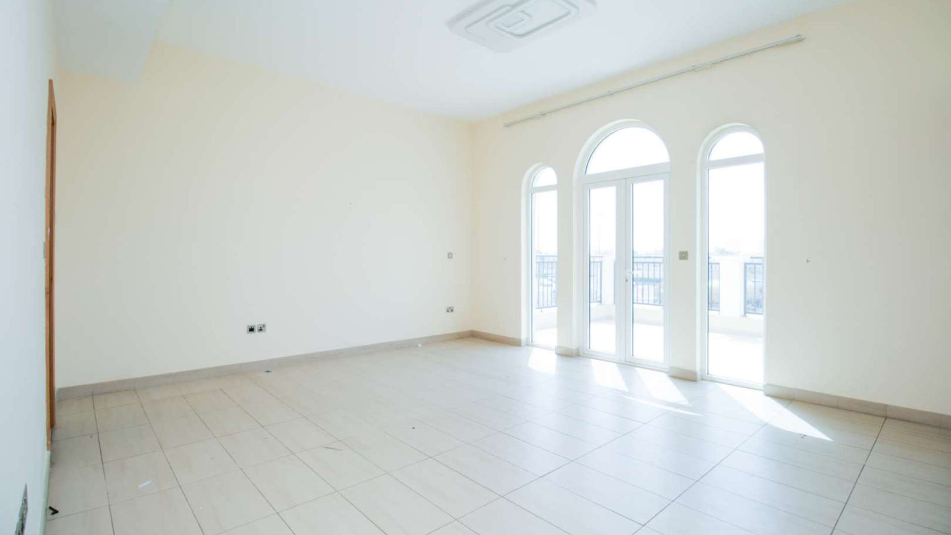 Bright empty room with tiled floor and large arched windows in Legacy Nova Villa
