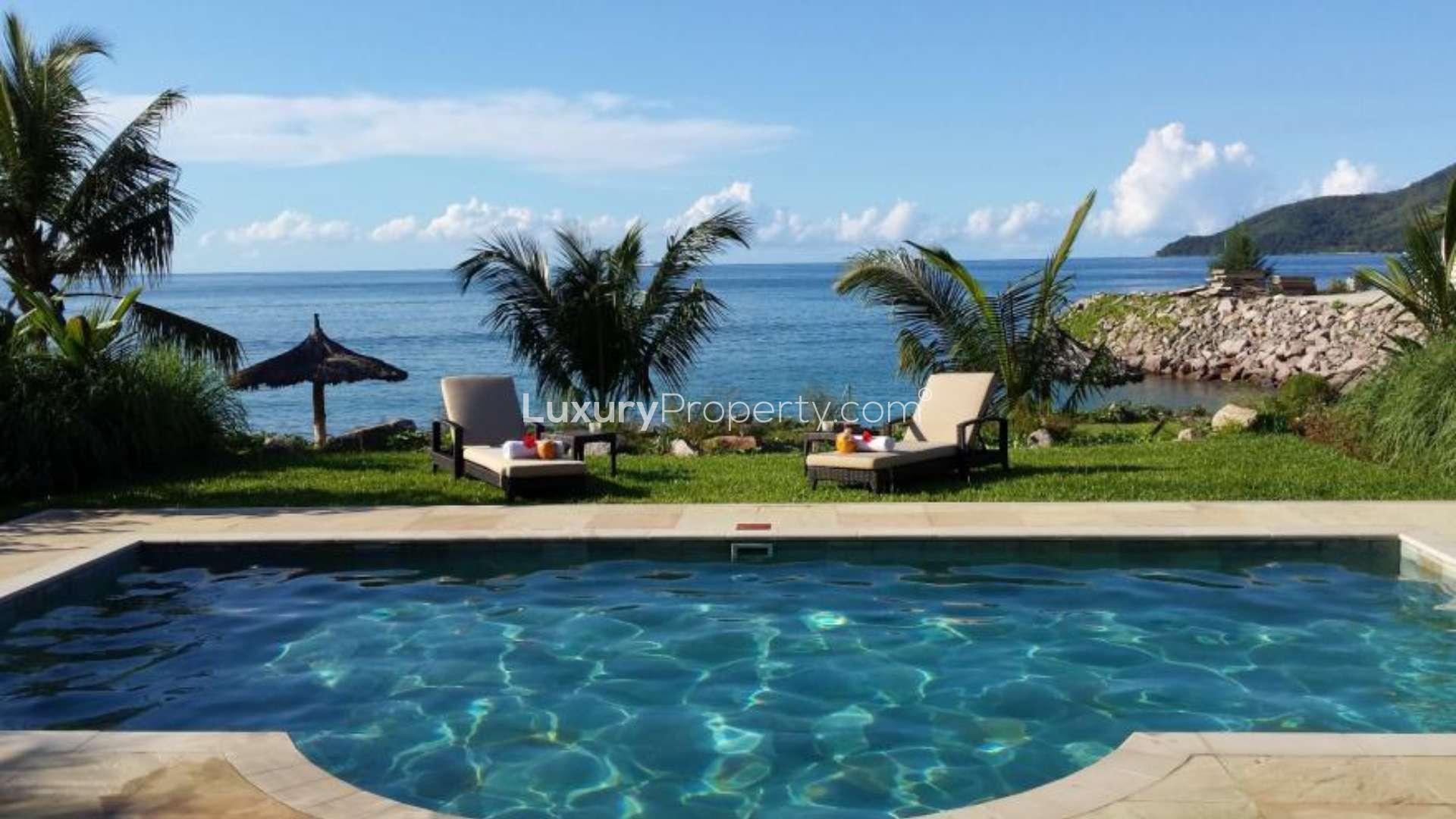 "Villa poolside view with loungers overlooking ocean, Eden Island, Maison for sale.",Luxurious Eden Island villa pool with ocean view, palm trees, and sun loungers