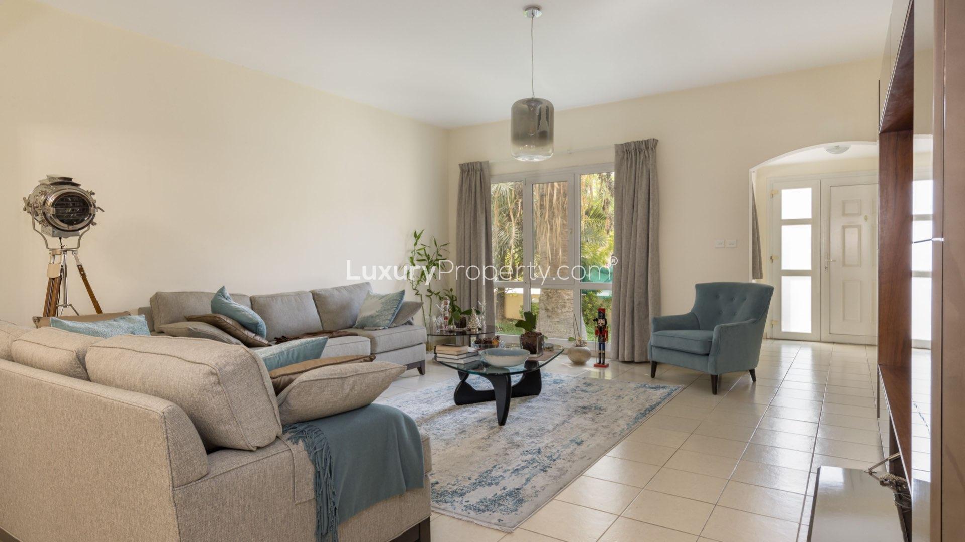 "Spacious villa backyard with covered patio in Meadows 1, ideal for family gatherings.",Living room of four-bedroom villa in Meadows 1 with modern decor and natural light