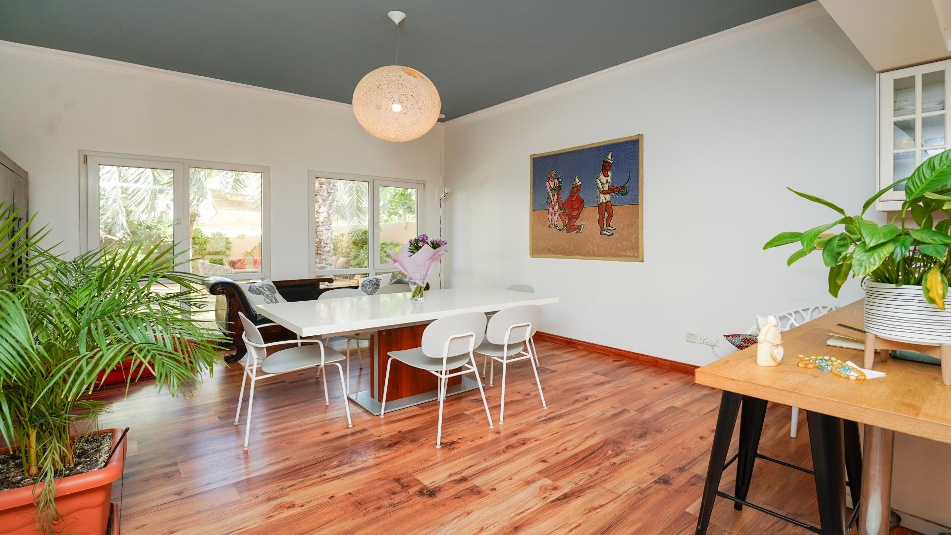 "Cozy villa interior with bookshelf, plants, and decorative wall in Meadows, Emirates Living.",Bright dining area in upgraded 4-bedroom villa, Meadows, Emirates Living, with garden view