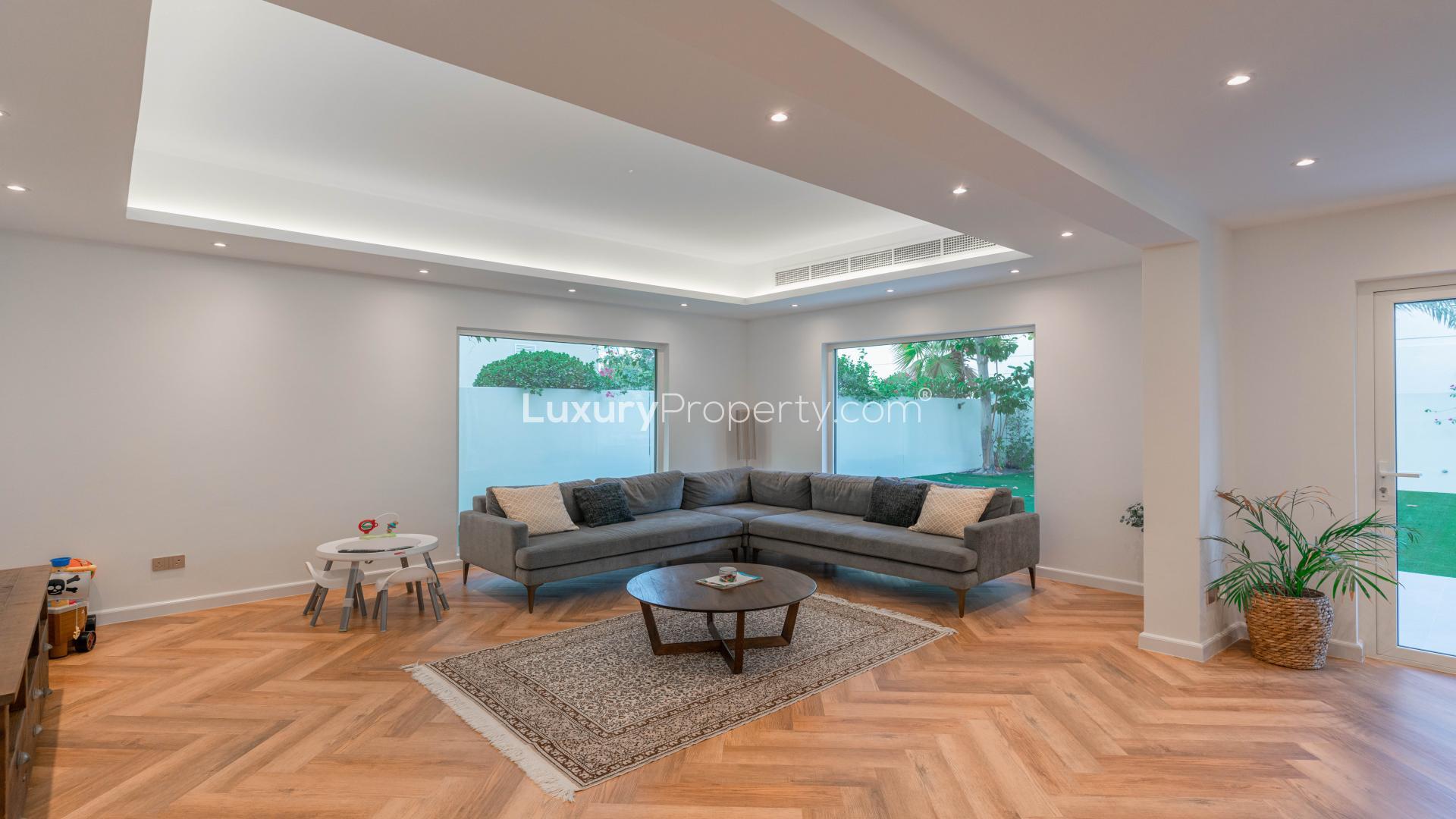 Fully renovated villa exterior in Meadows 2 with two-car garage, lush greenery, and blue sky