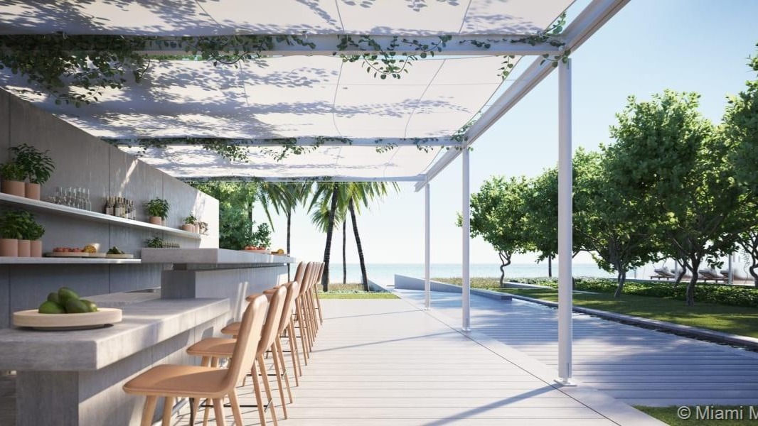 Oceanfront villa poolside with loungers, palm trees, and ocean view at 8701 Collins Ave