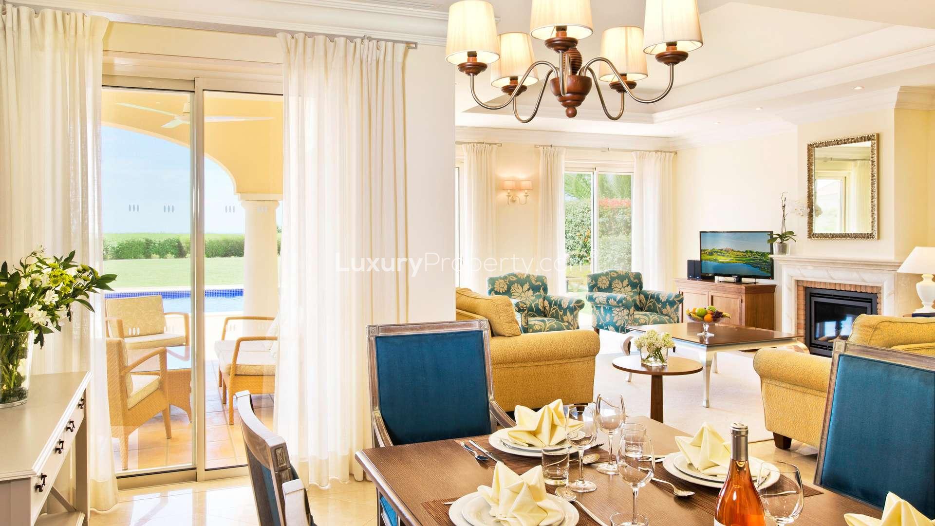 Luxurious living room in Monte Rei villa, Algarve, featuring fireplace and garden view