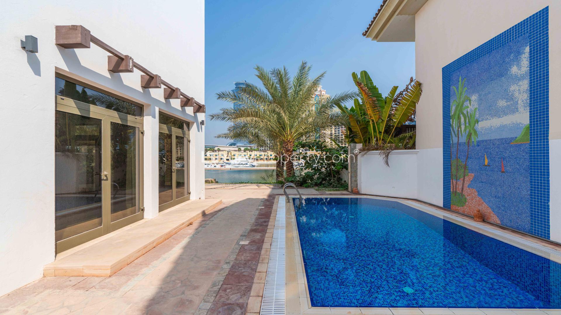 "Grand 4-Bed Villa Exterior with Garage on Palm Jumeirah, Frond P, for Sale.",Modern kitchen interior in 4-bed Palm Jumeirah villa, featuring sleek cabinets and dining table
