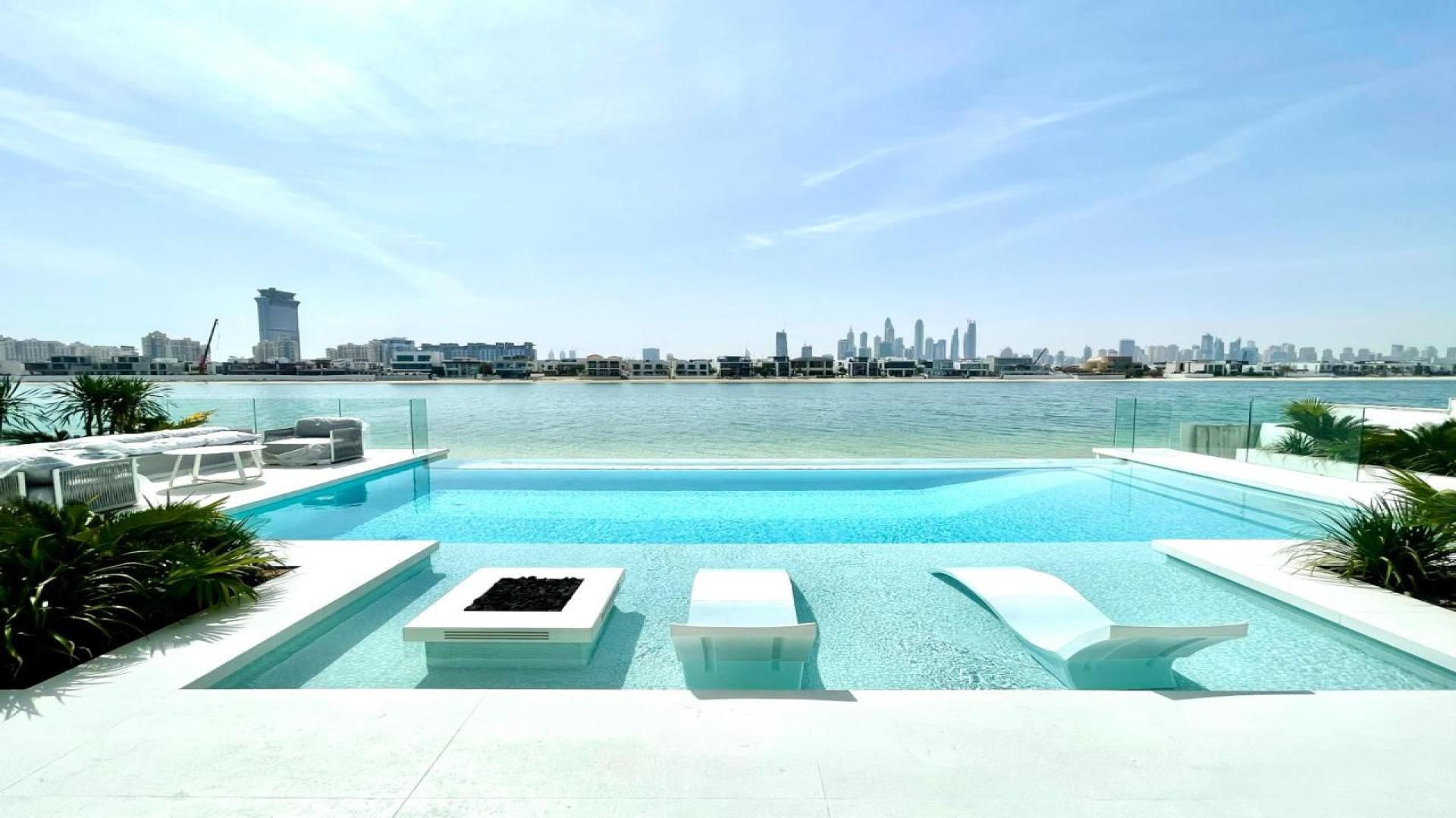Luxurious open-plan living room with modern decor and stunning waterfront views in Palm Jumeirah villa