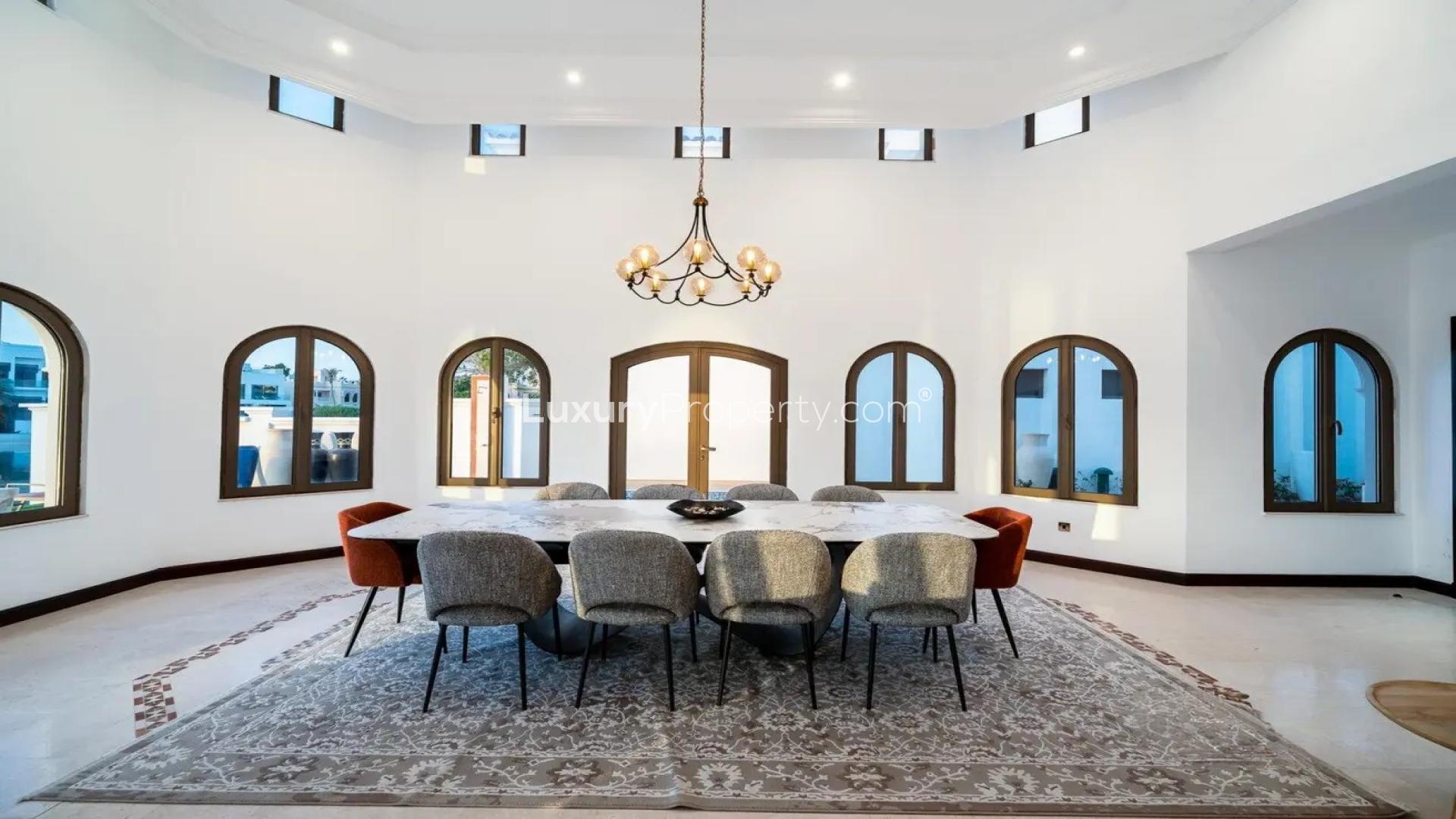 Luxurious dining area in Palm Jumeirah villa with pool view, arched windows, elegant chandelier