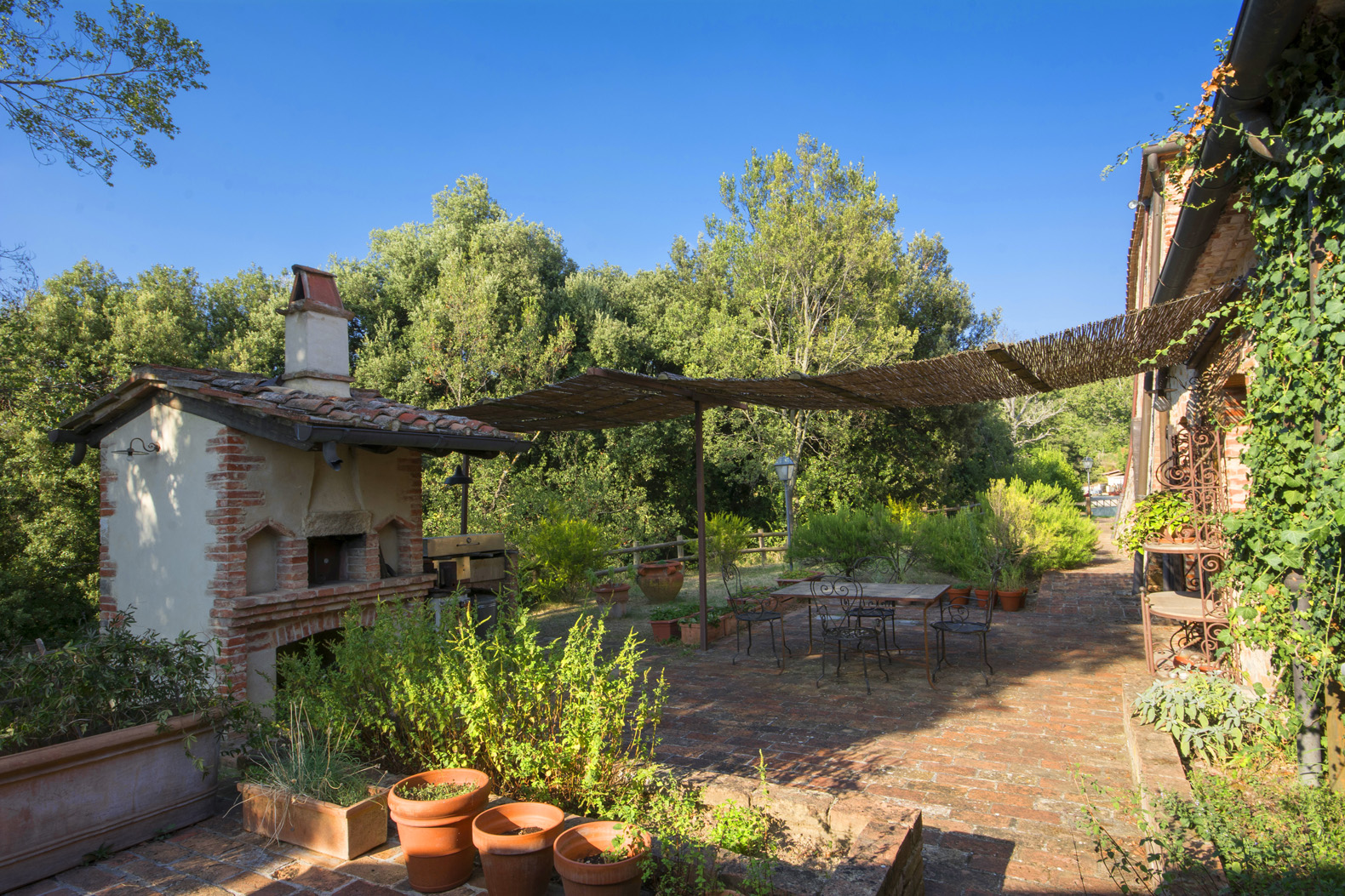 Sun-themed wall art and terracotta planter on Siena villa exterior, Tenuta Malacoda estate