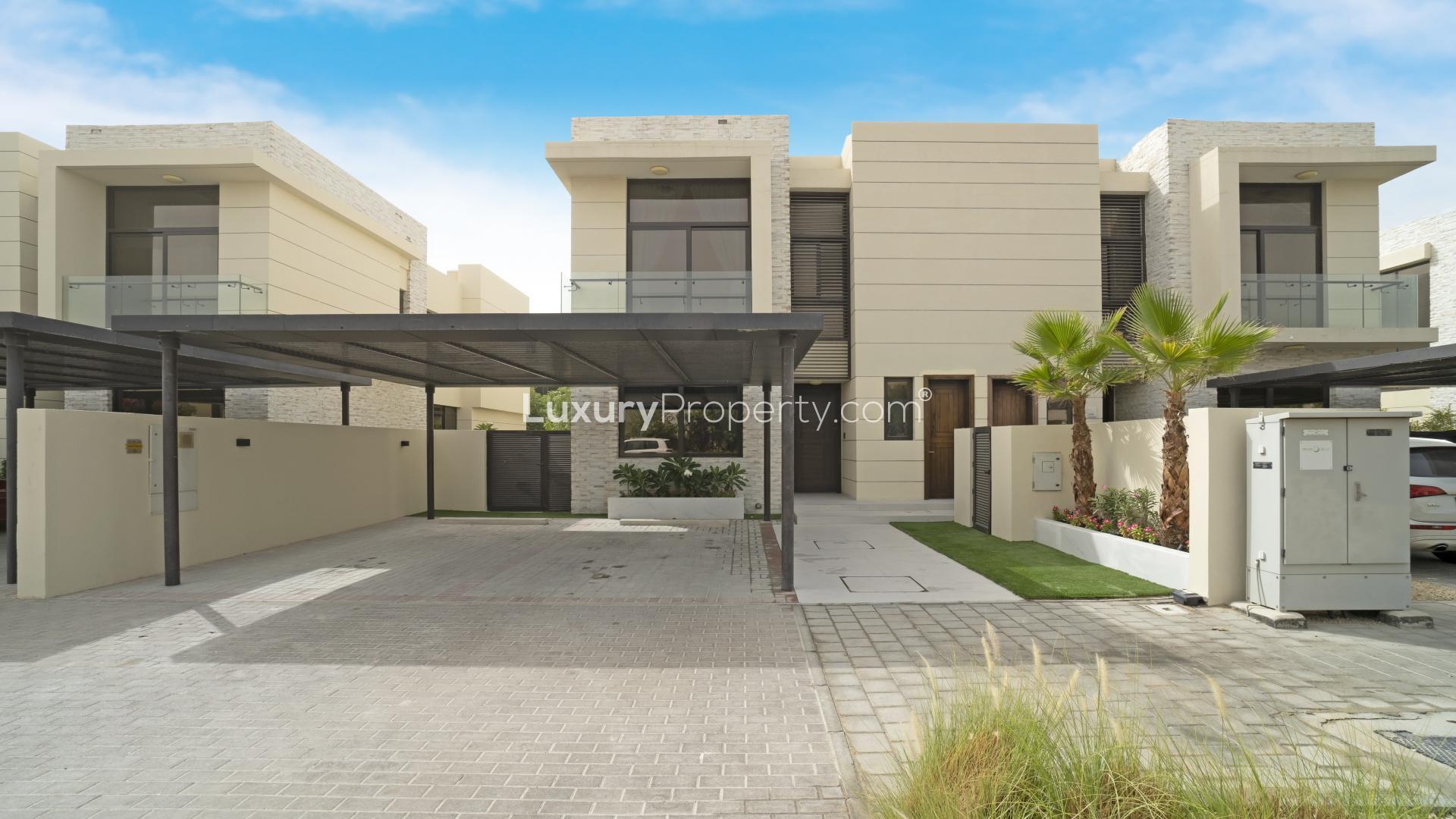 Modern villa backyard with pool, lush greenery, and seating area in Damac Hills