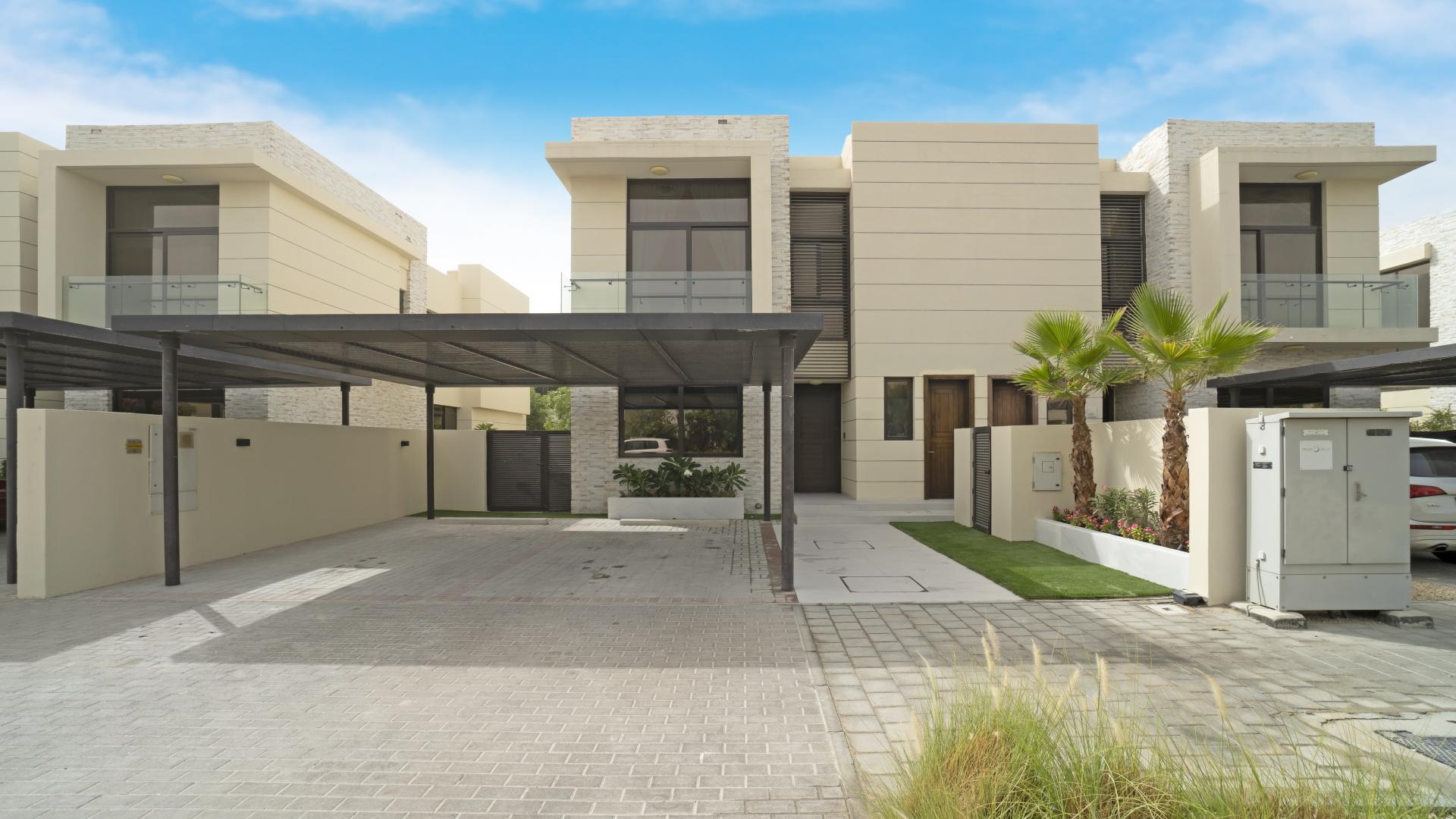 Modern villa backyard with pool, lush greenery, and seating area in Damac Hills
