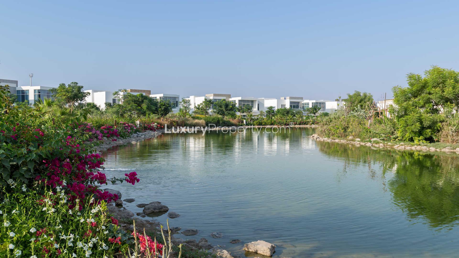 Pathway with lush greenery and water view at The Nest, Al Barari villa community