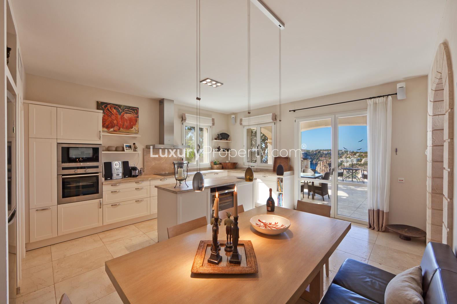 "Spanish villa terrace with ocean view, pool, and lush greenery in Port d'Andratx, Mallorca.",Kitchen and dining area in Spanish villa with ocean view, Villa Cala Llamp, Mallorca