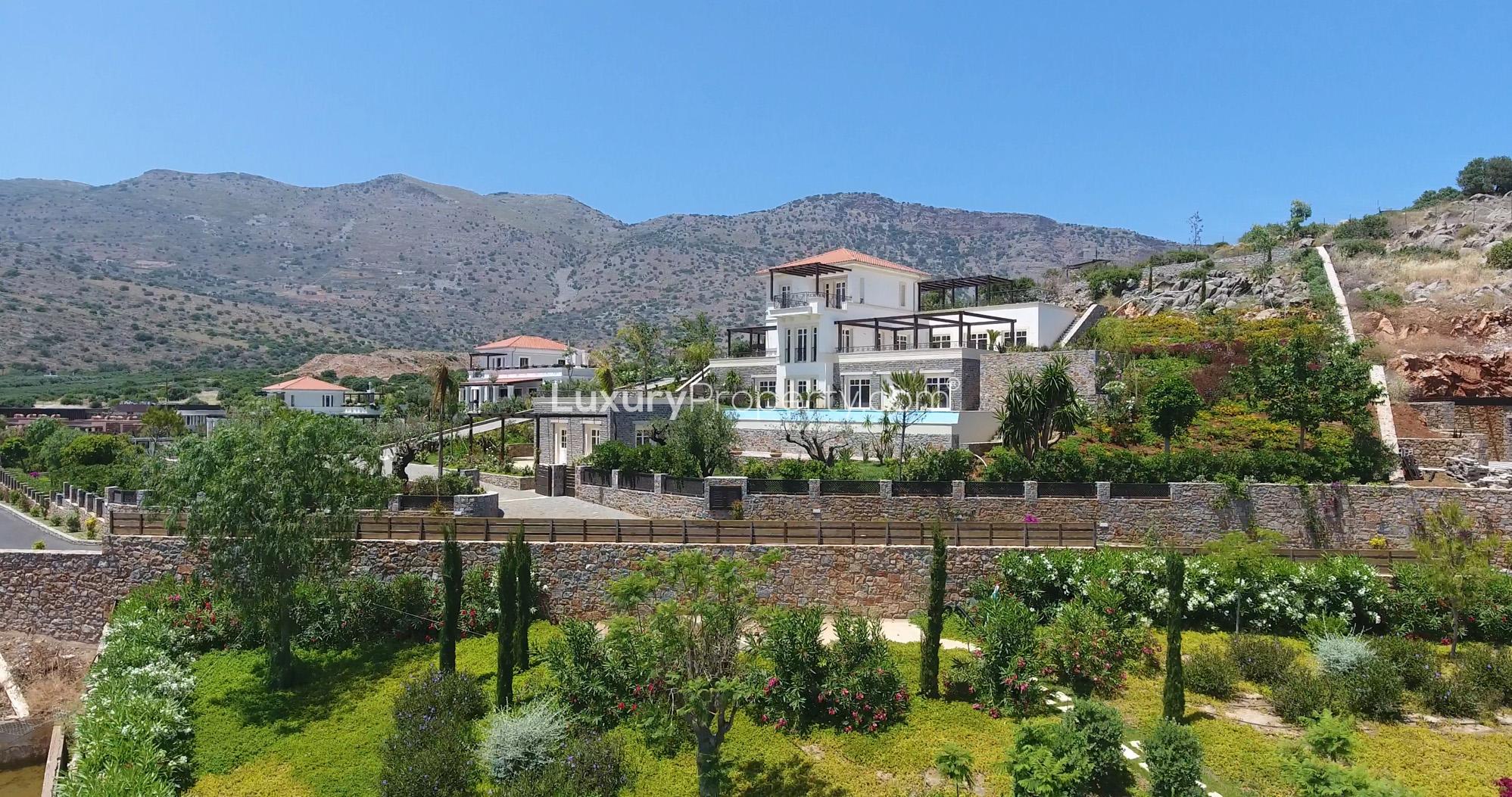 Four-bedroom waterfront villa with lush garden, pool, and stone walls in Crete, Greece