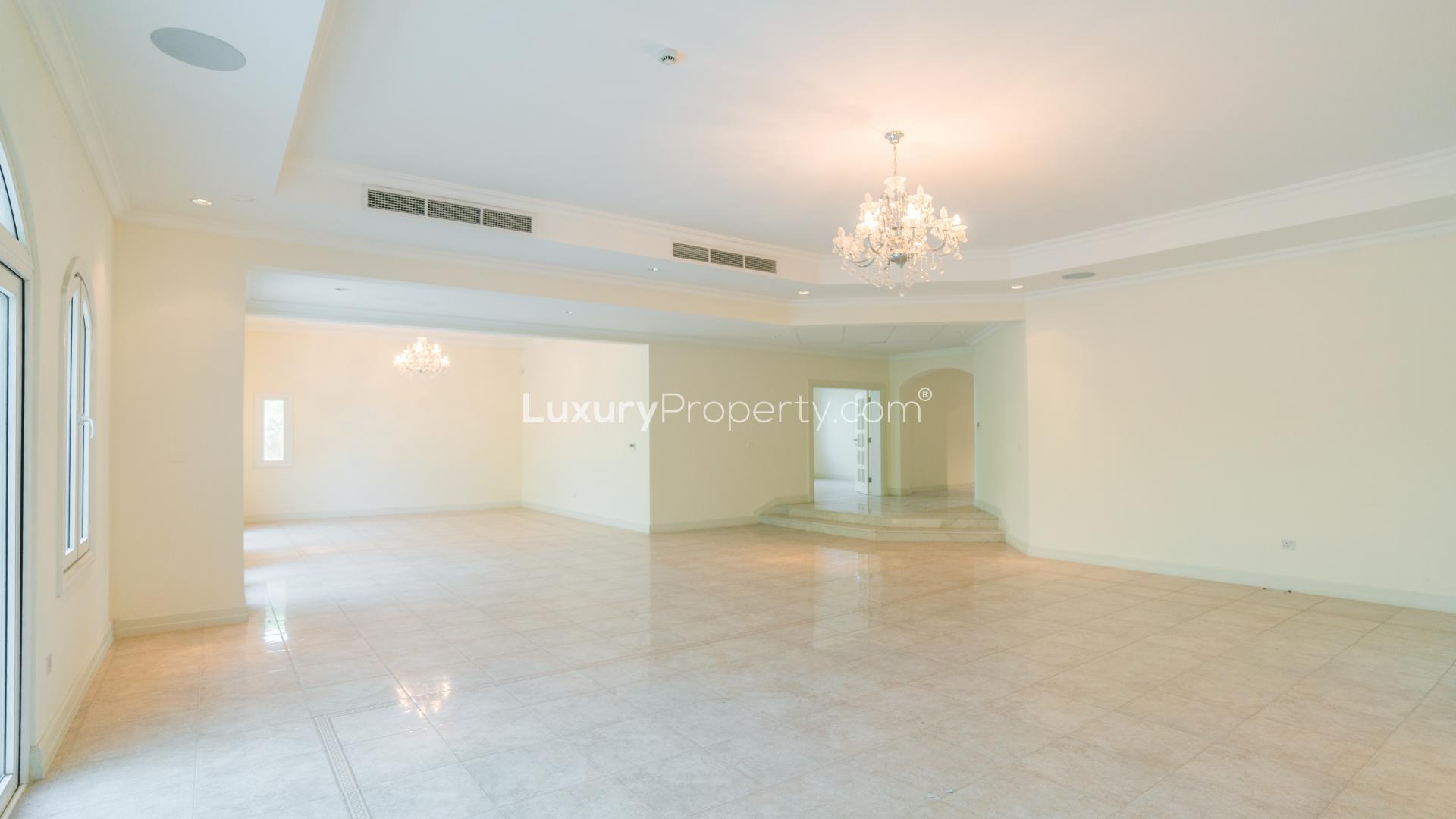 Spacious living room with chandelier and large windows in Jumeirah Golf Estates villa for rent